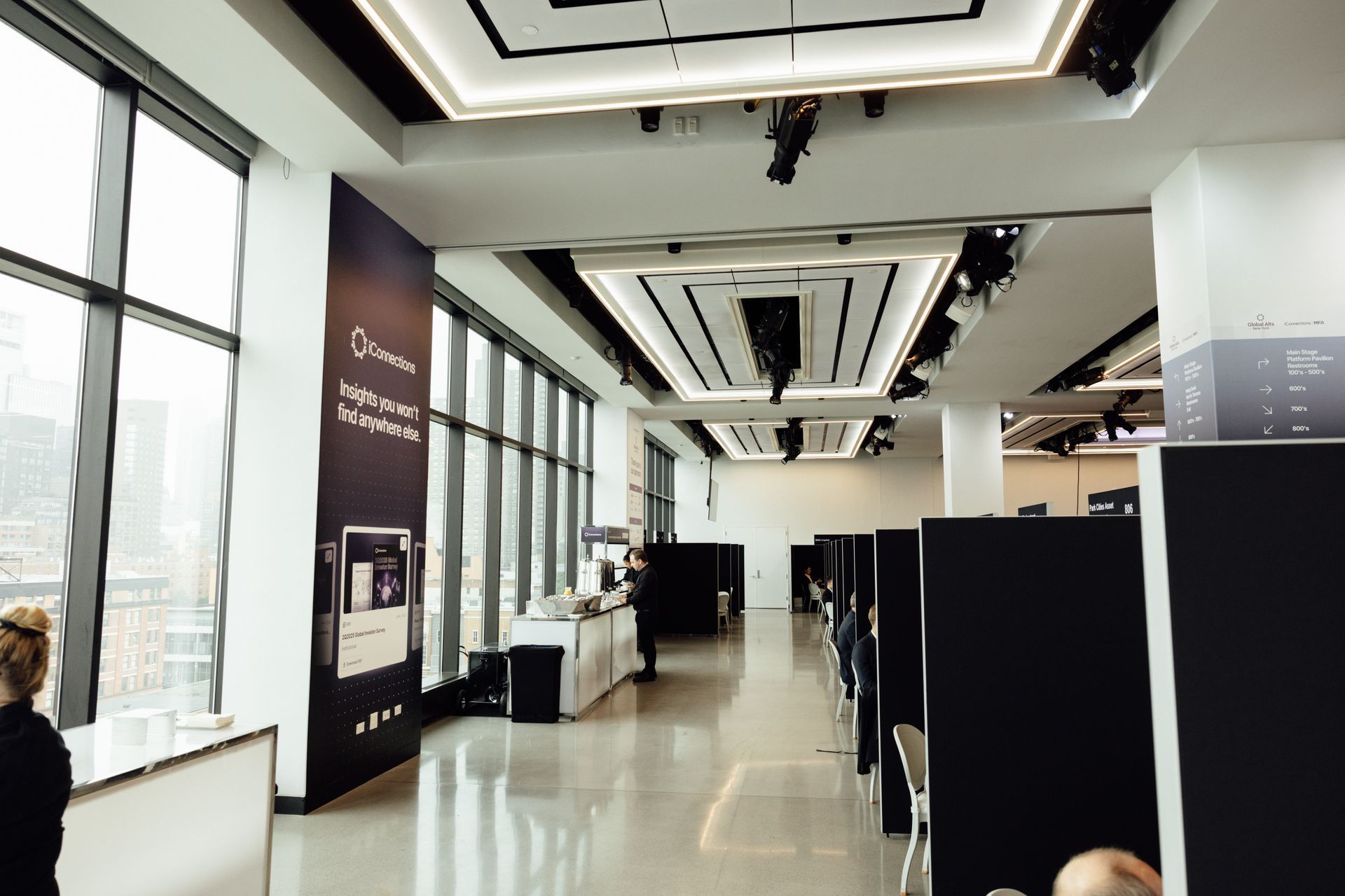 Modern office interior with large windows, cubicles, and a long hallway.