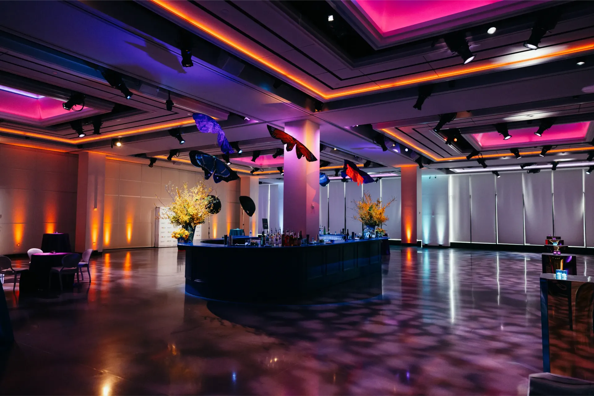 A large room with a lot of lights on the ceiling and tables and chairs.