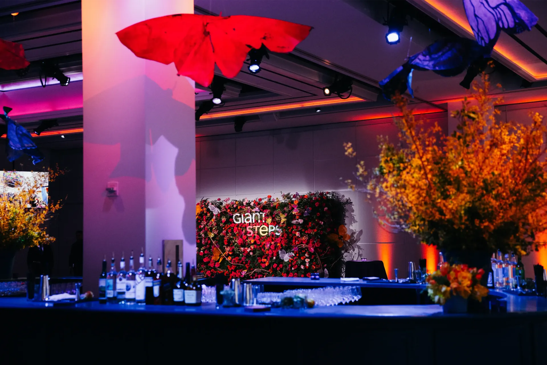 A large room with a bar and a wall with flowers and the word stella on it