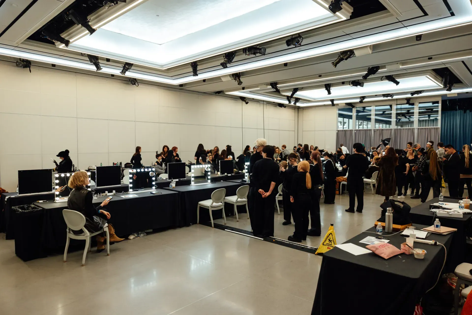 A large room filled with people standing around tables and chairs.