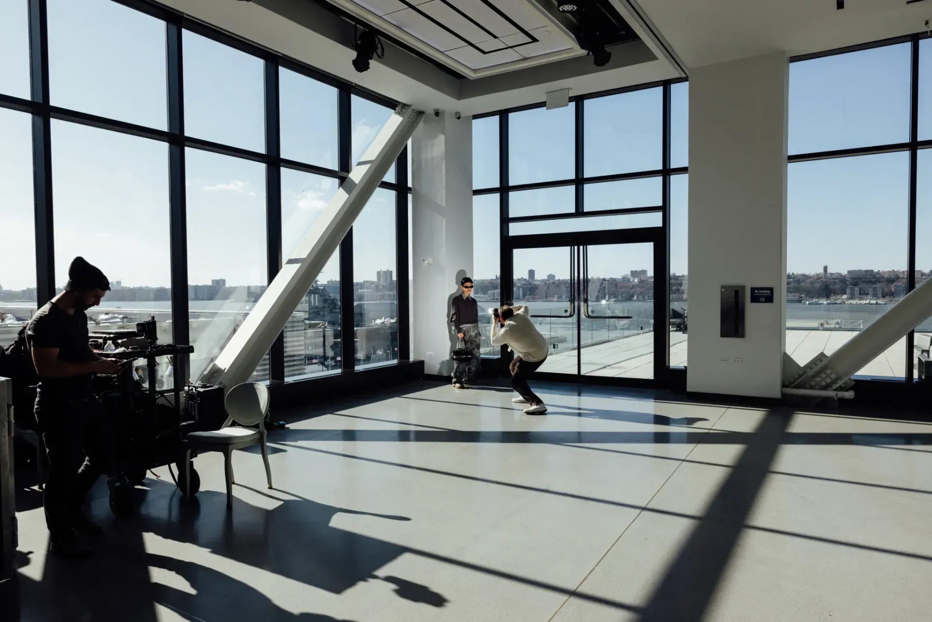 A man is taking a picture of another man in a large room with lots of windows