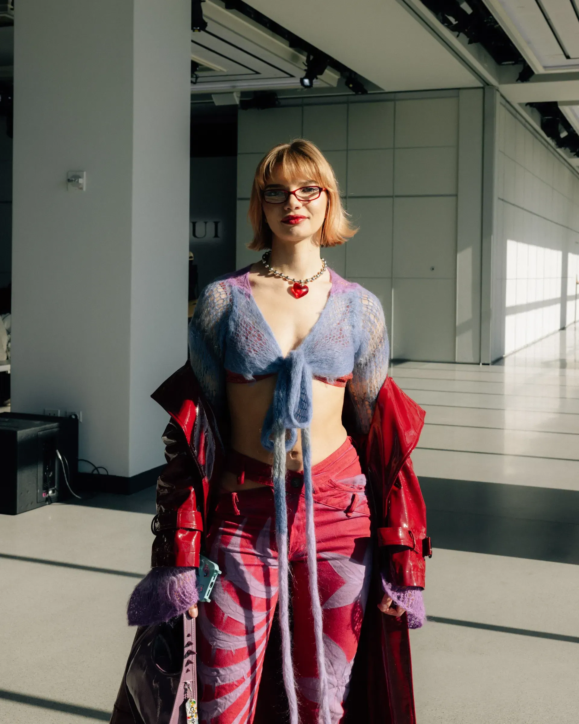 A woman in a purple top and red pants is standing in a hallway