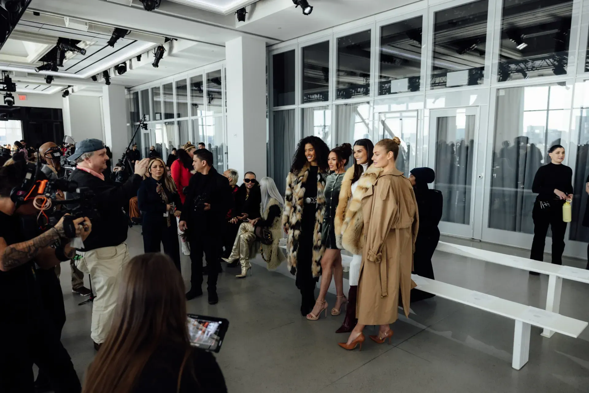 A group of people are standing in a room with a lot of windows.