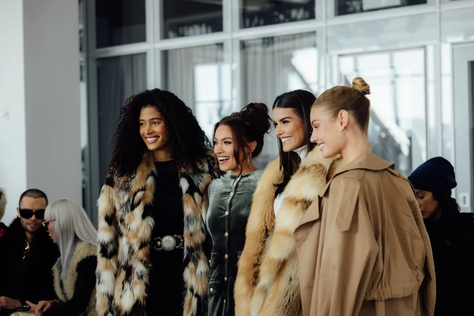 A group of women wearing fur coats are posing for a picture.