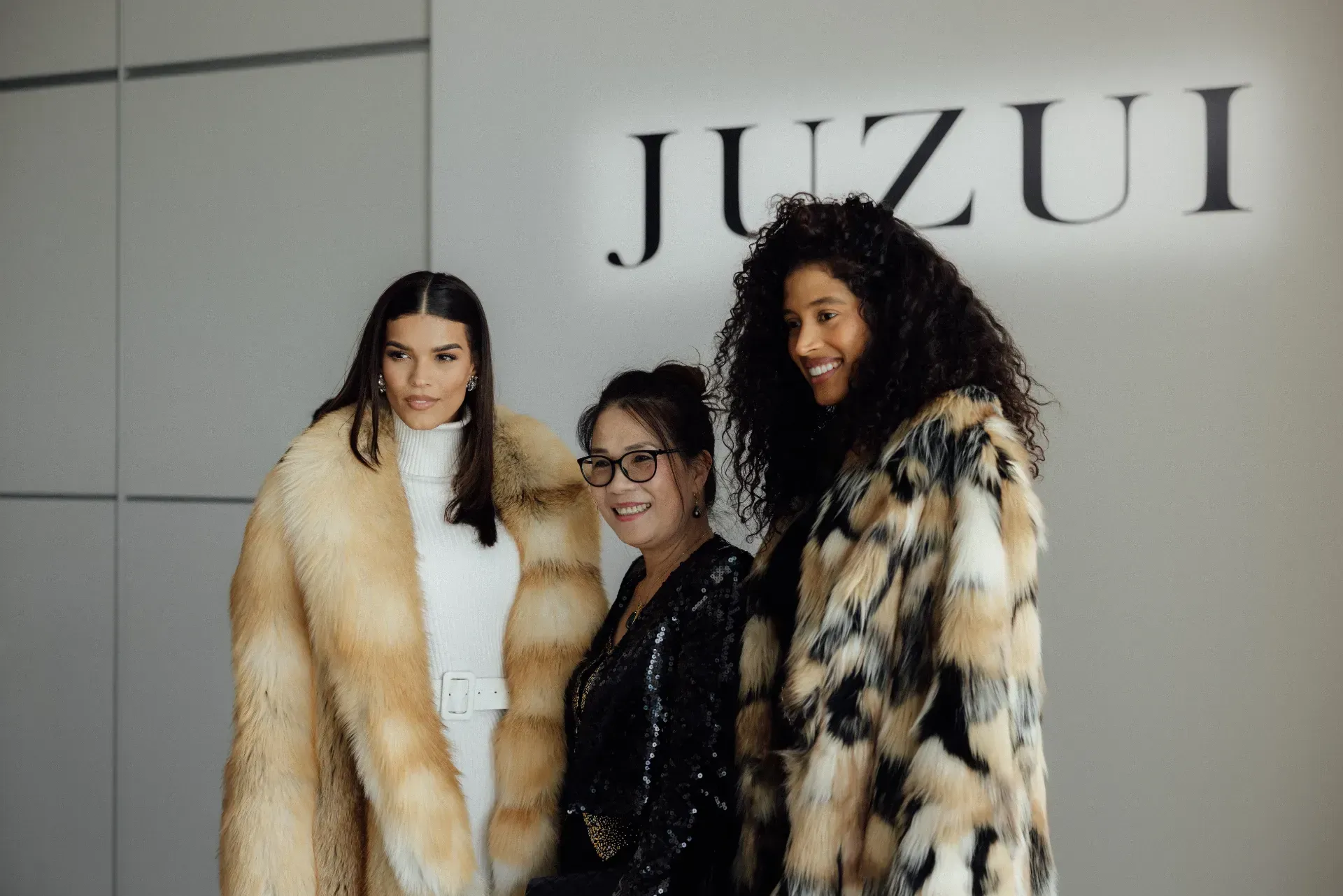 Three women wearing fur coats are posing for a picture.