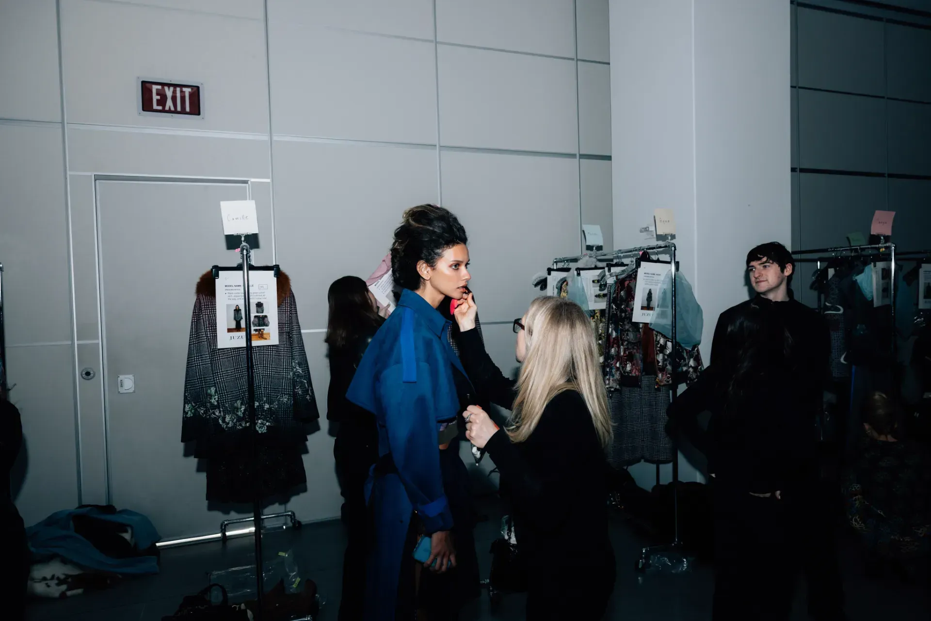 A group of people are standing in a room with a sign that says exit.