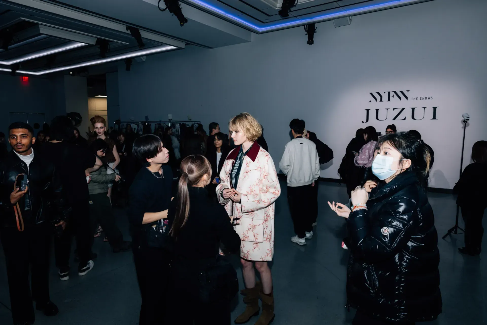 A group of people are standing in a room talking to each other.