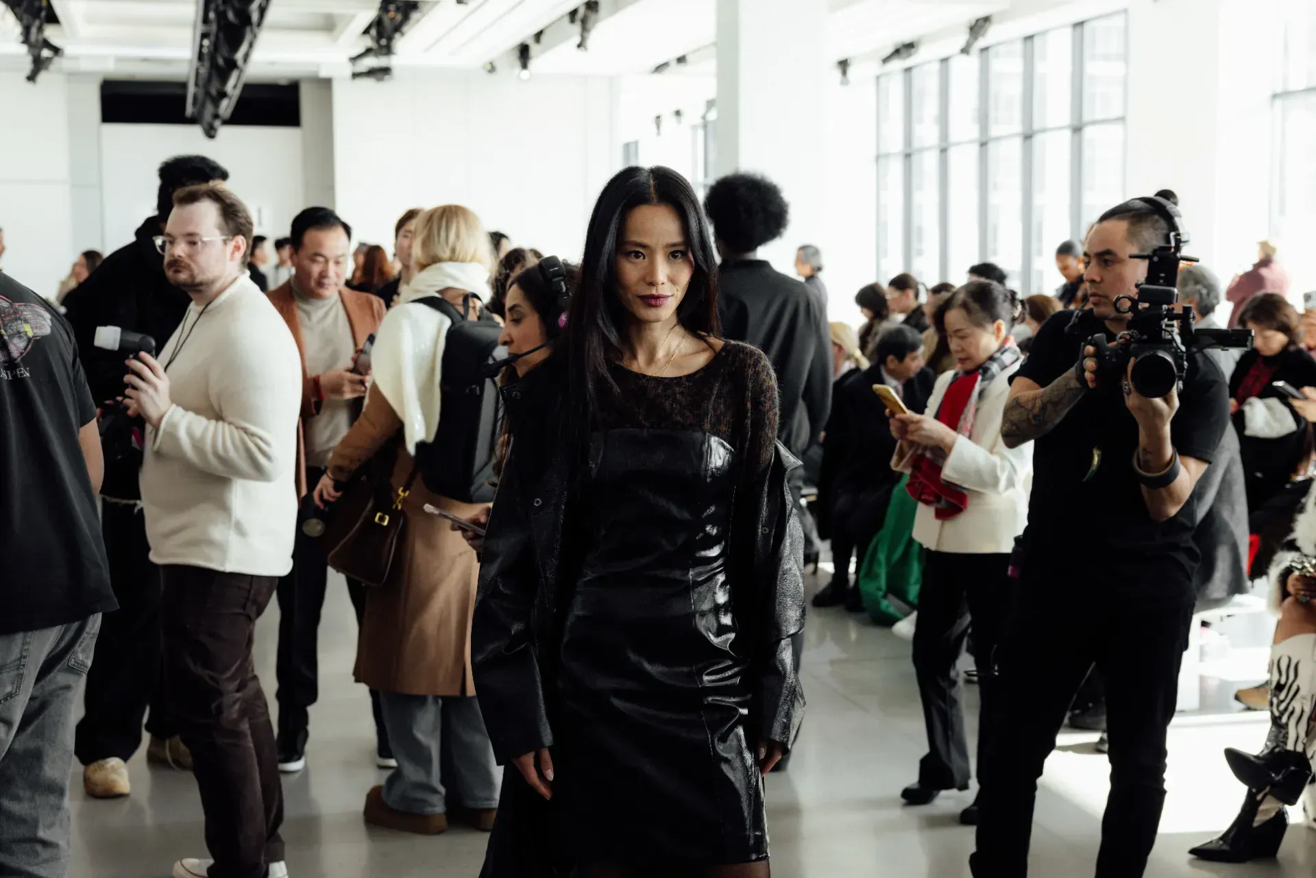 A woman in a black dress is walking through a crowd of people.
