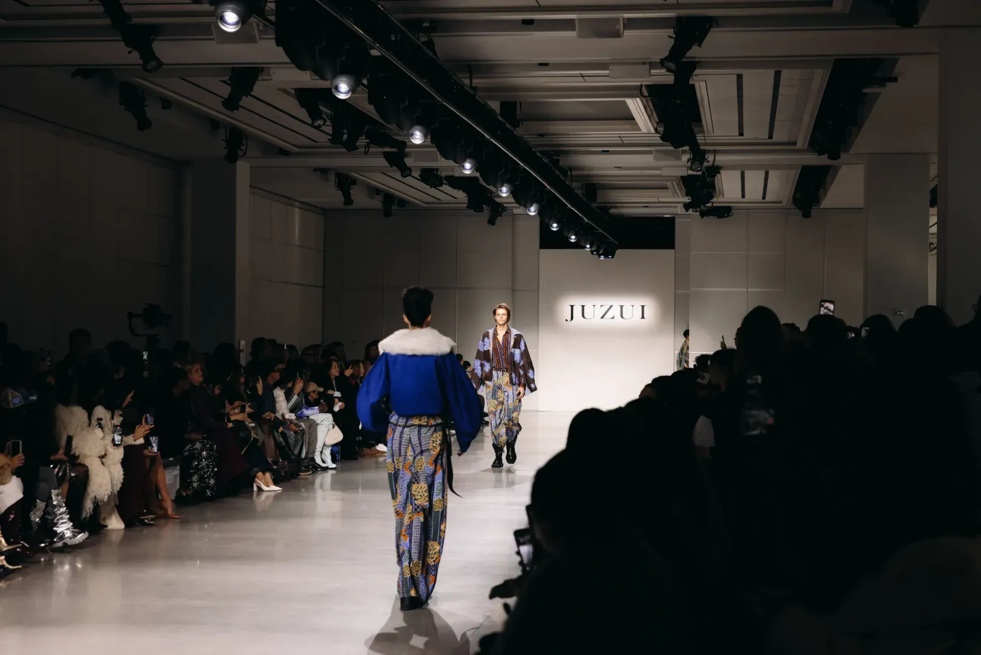 A group of models are walking down a runway at a fashion show.