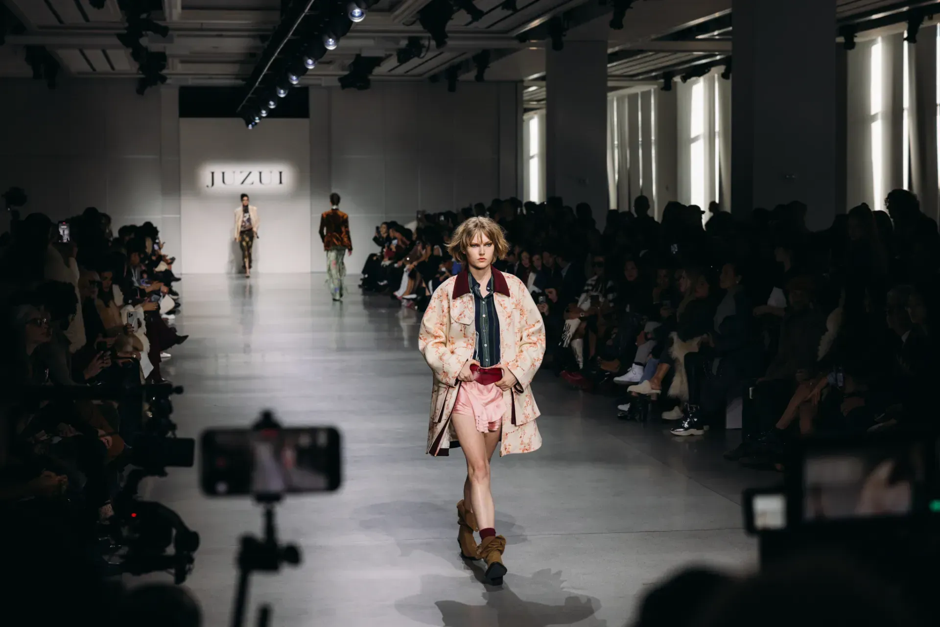 A model is walking down the runway at a fashion show.