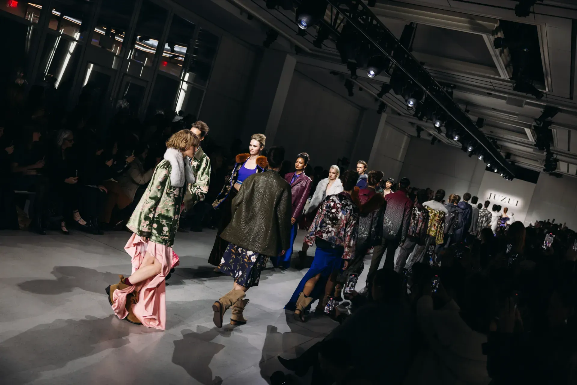 A group of people are dancing on a runway at a fashion show.