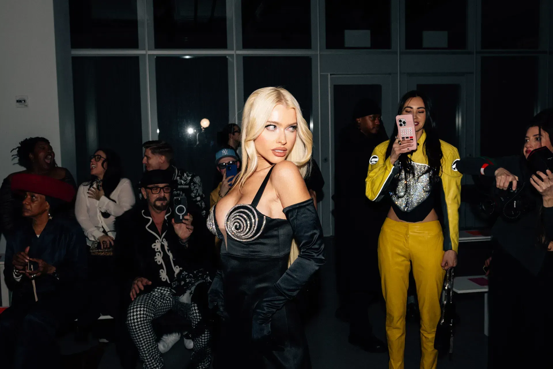 A woman in a black dress is standing in front of a crowd of people.