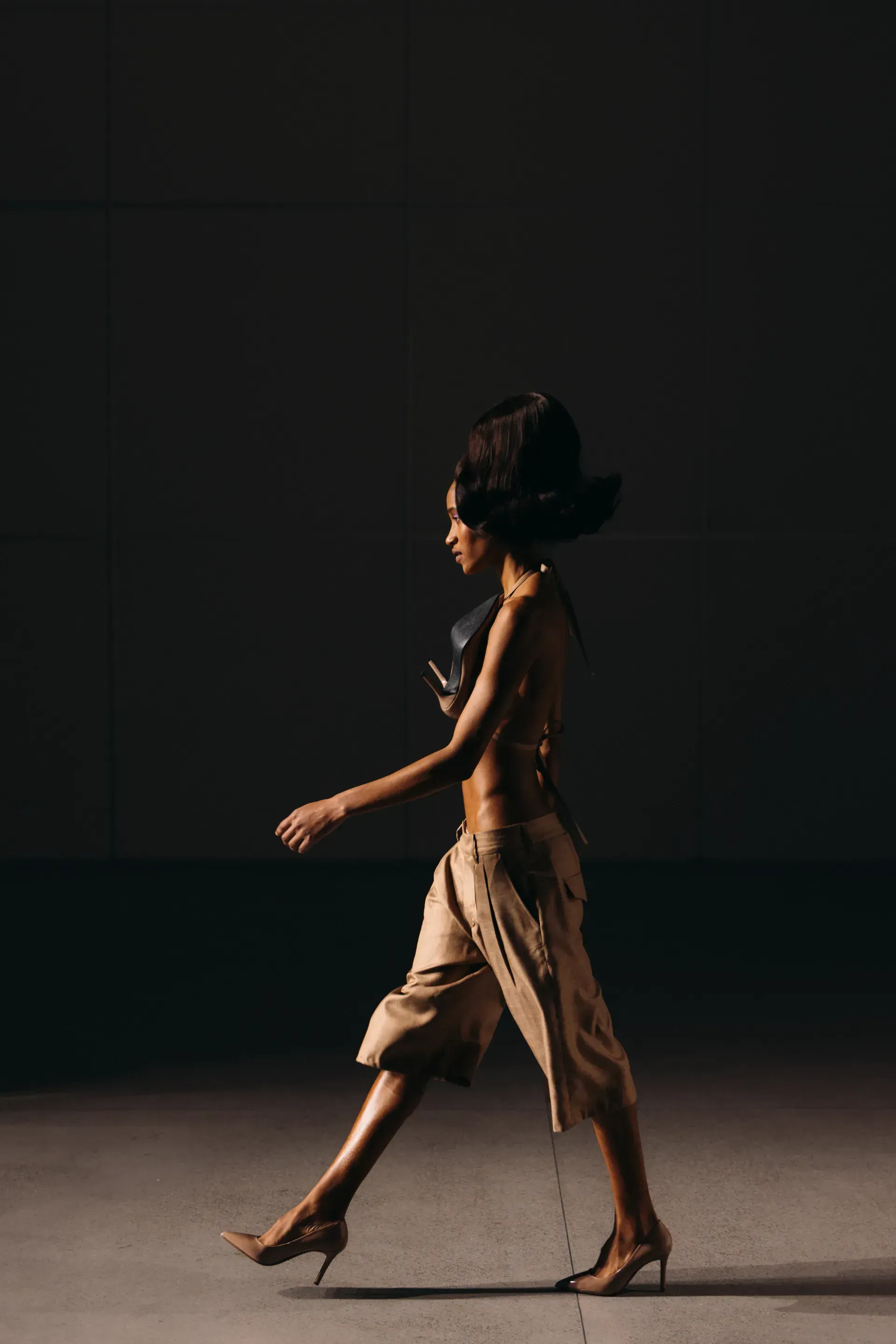 A woman is walking in a dark room with her hair blowing in the wind.