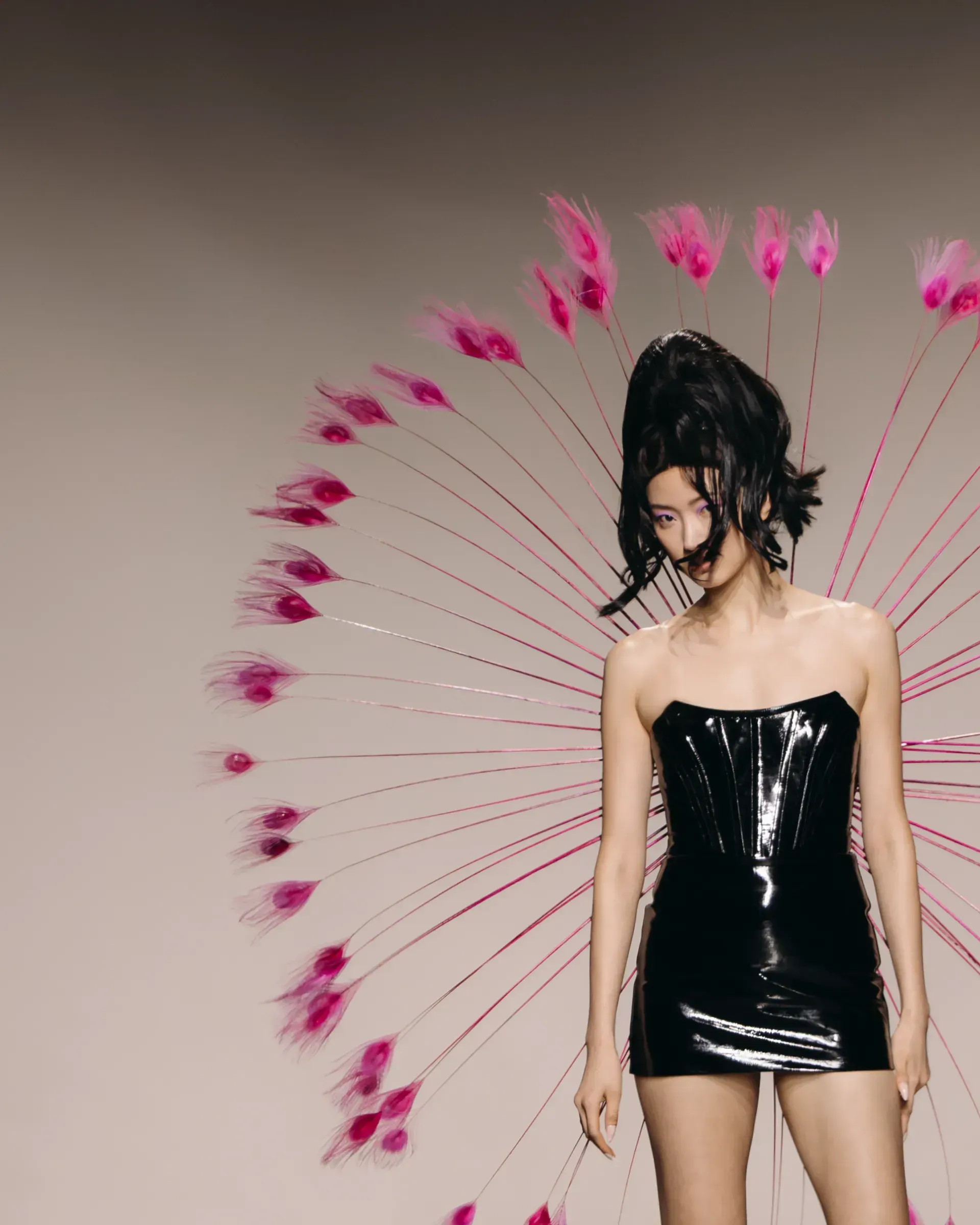 A woman in a black dress is standing in front of a circle of pink flowers
