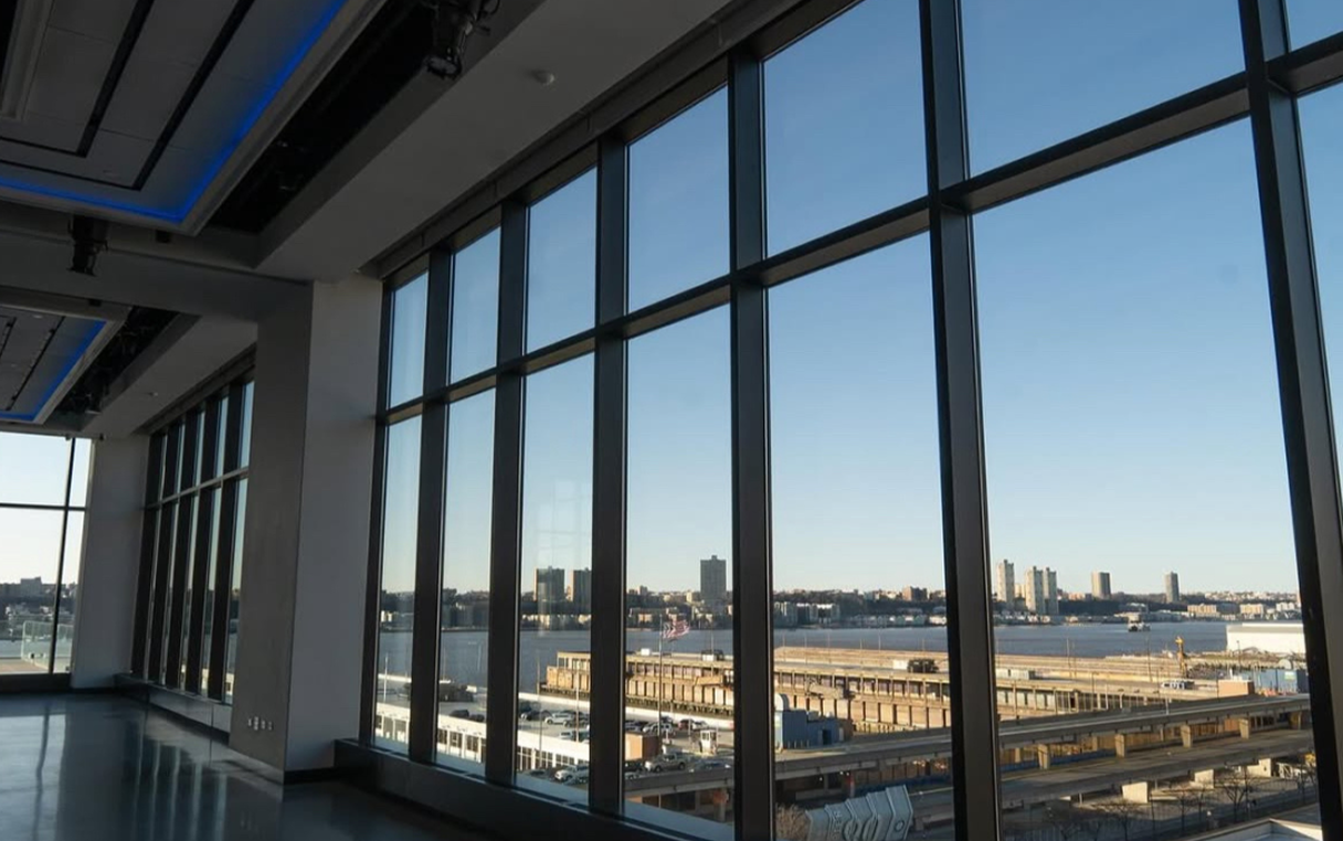 Interior view through large windows of a city skyline on a sunny day.