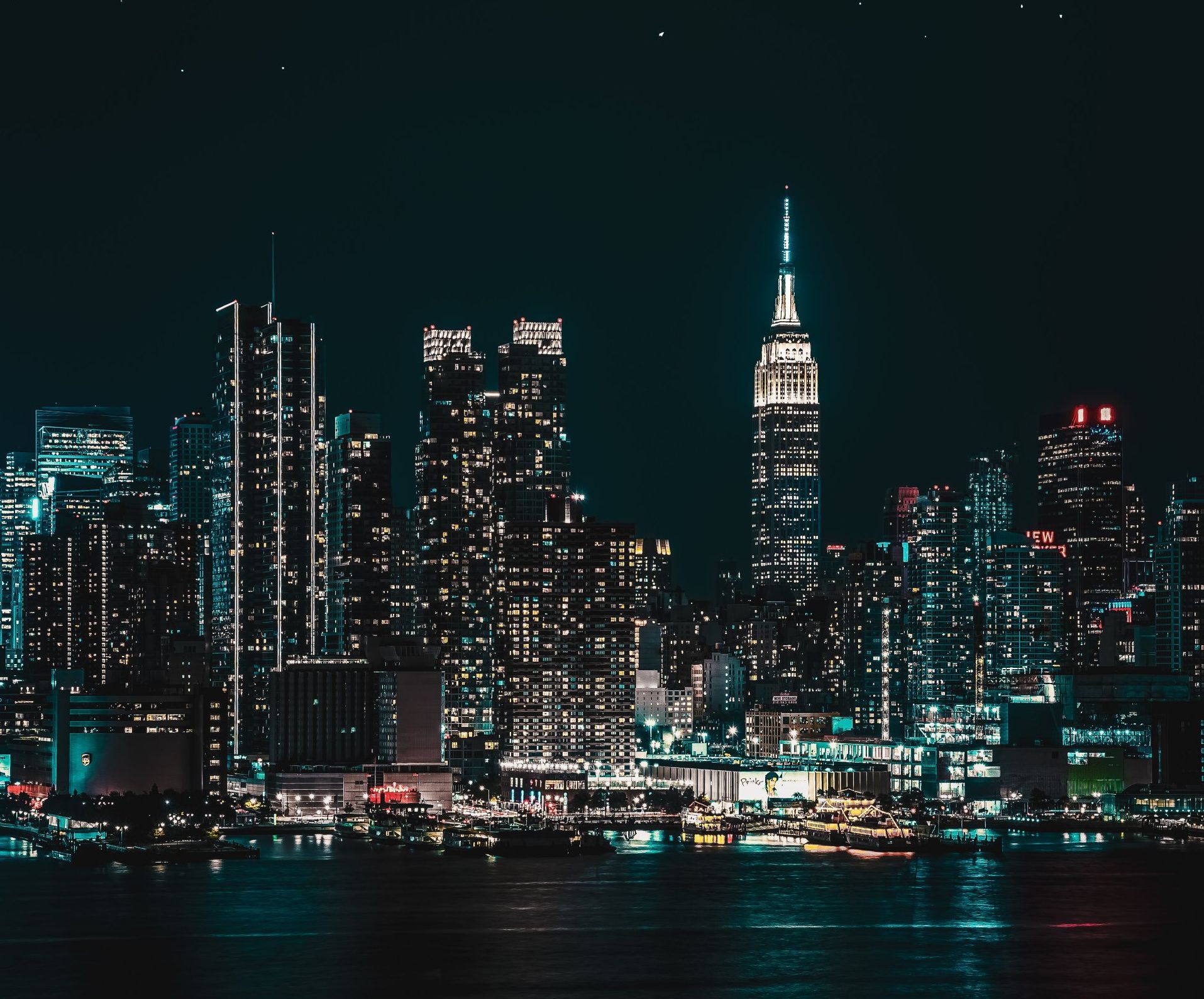 A city skyline at night with the empire state building in the foreground