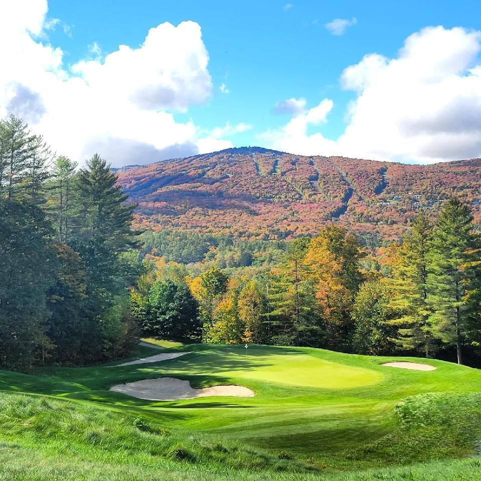 A golf course with trees and mountains in the background