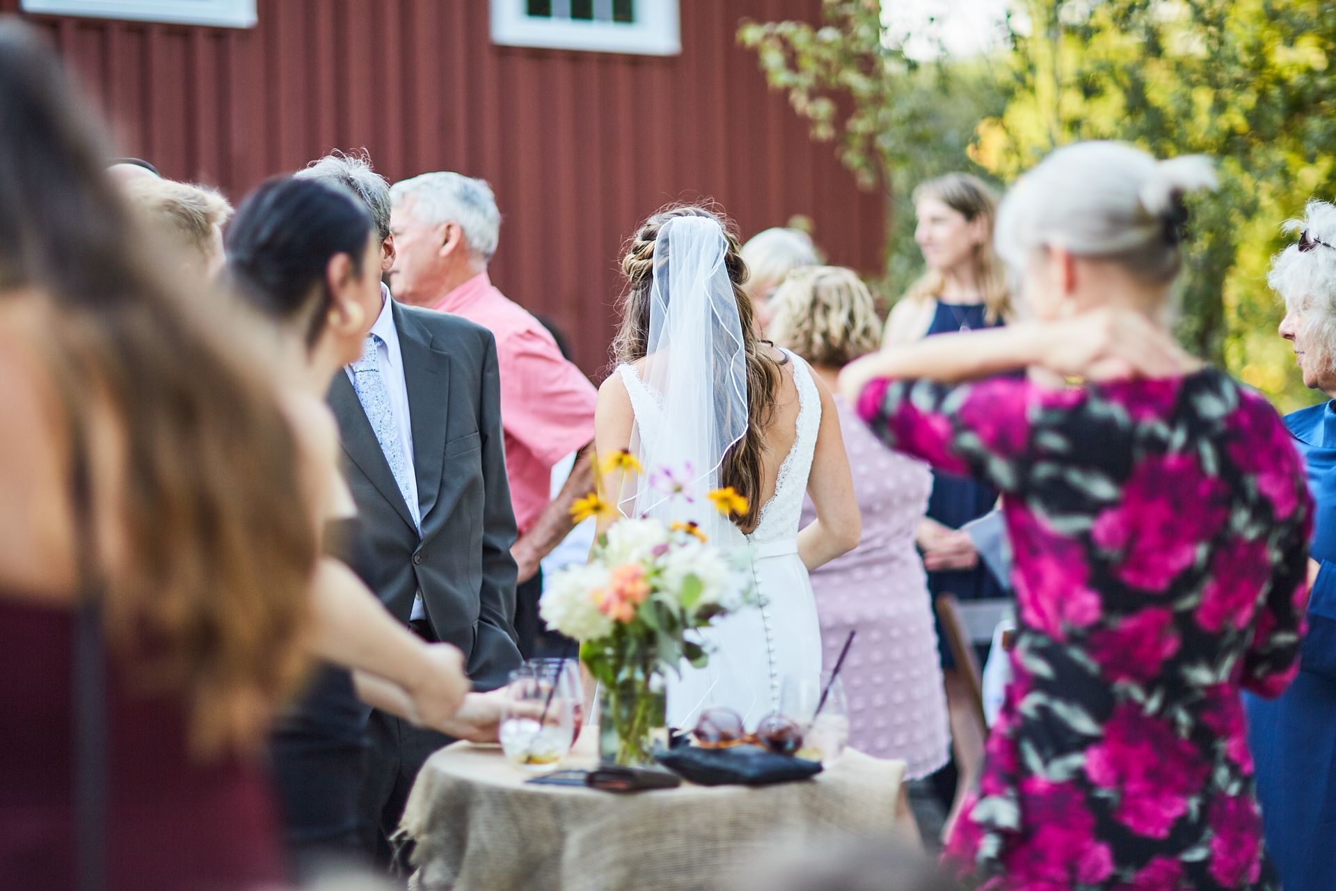 A bride and groom are standing in a crowd of people at a wedding reception.