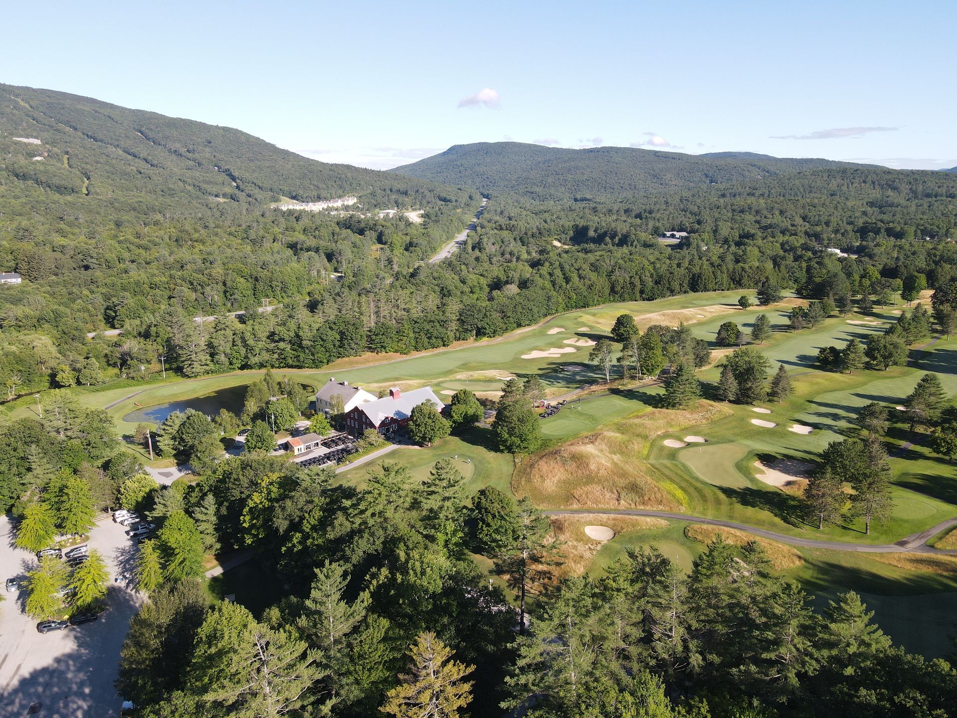 An aerial view of a golf course surrounded by trees and mountains.