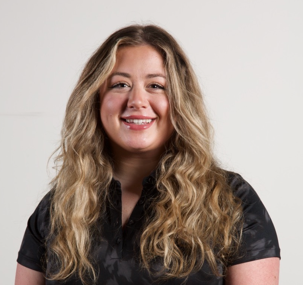 A woman with long blonde hair is smiling and wearing a black shirt