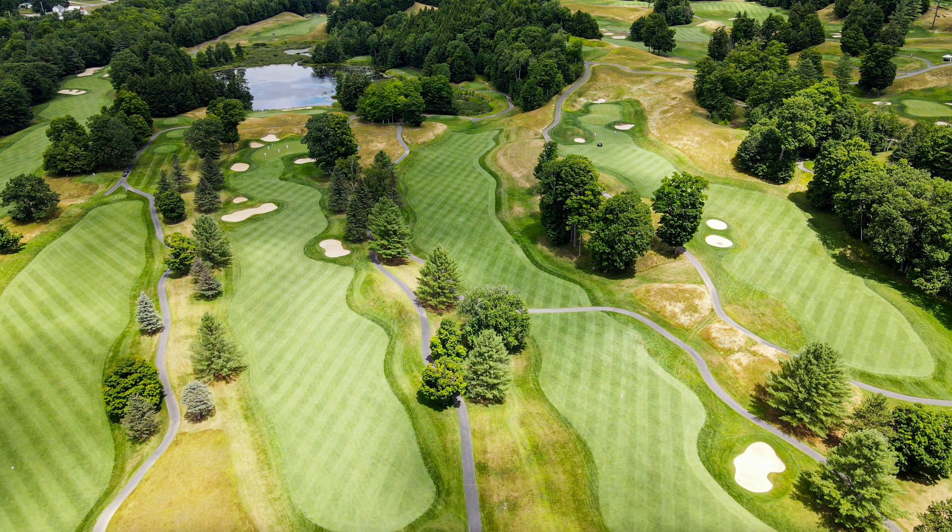 An aerial view of a golf course surrounded by trees and a lake.