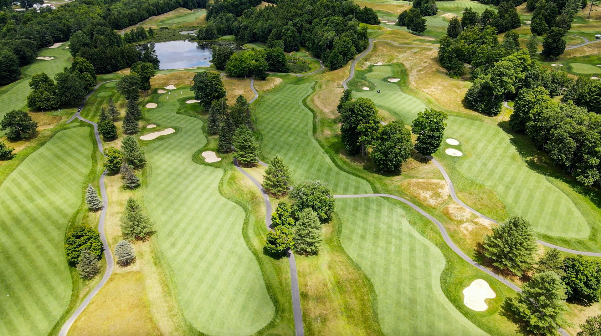 An aerial view of a golf course surrounded by trees and a lake.