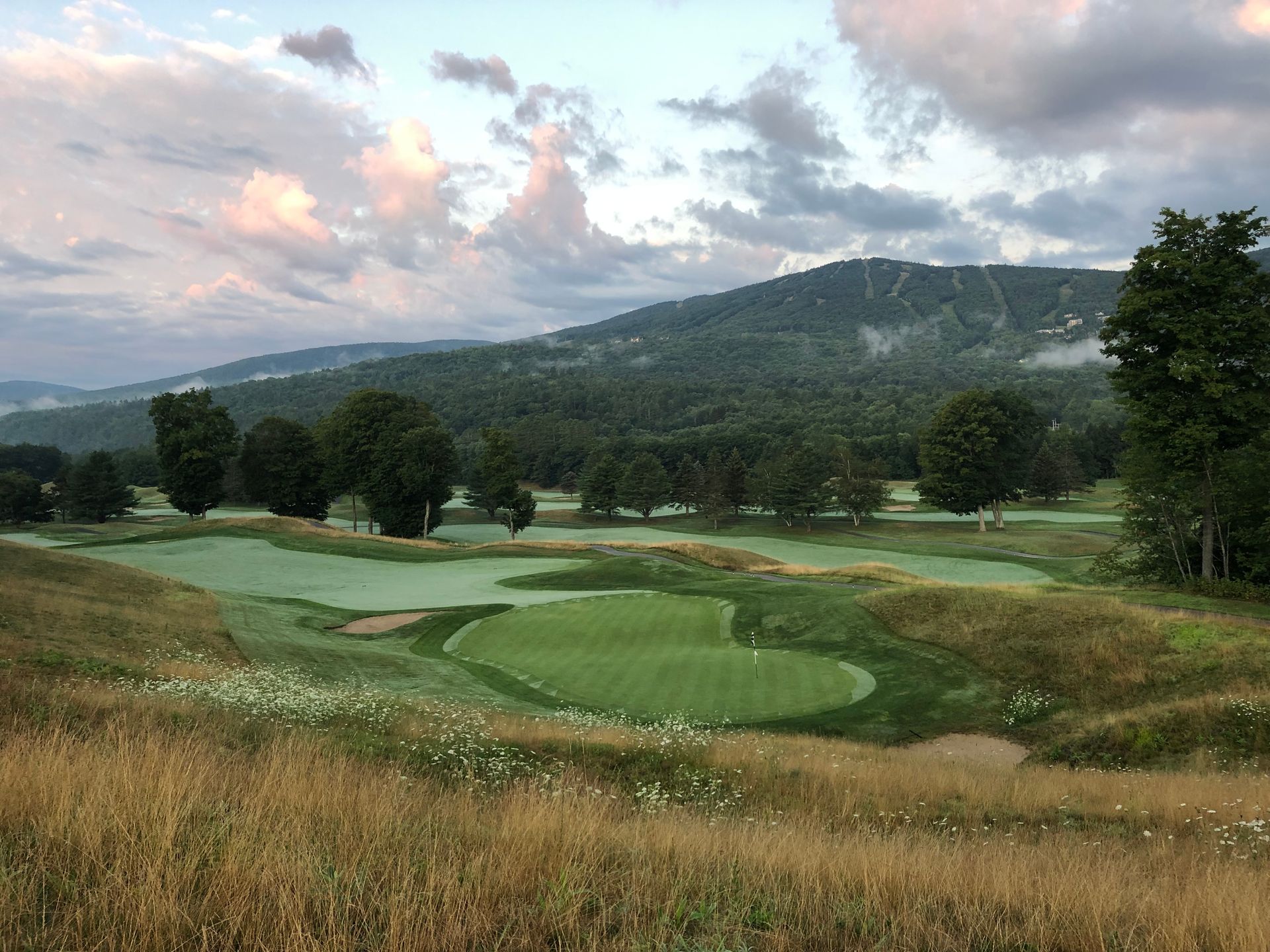 A view of a golf course with mountains in the background.