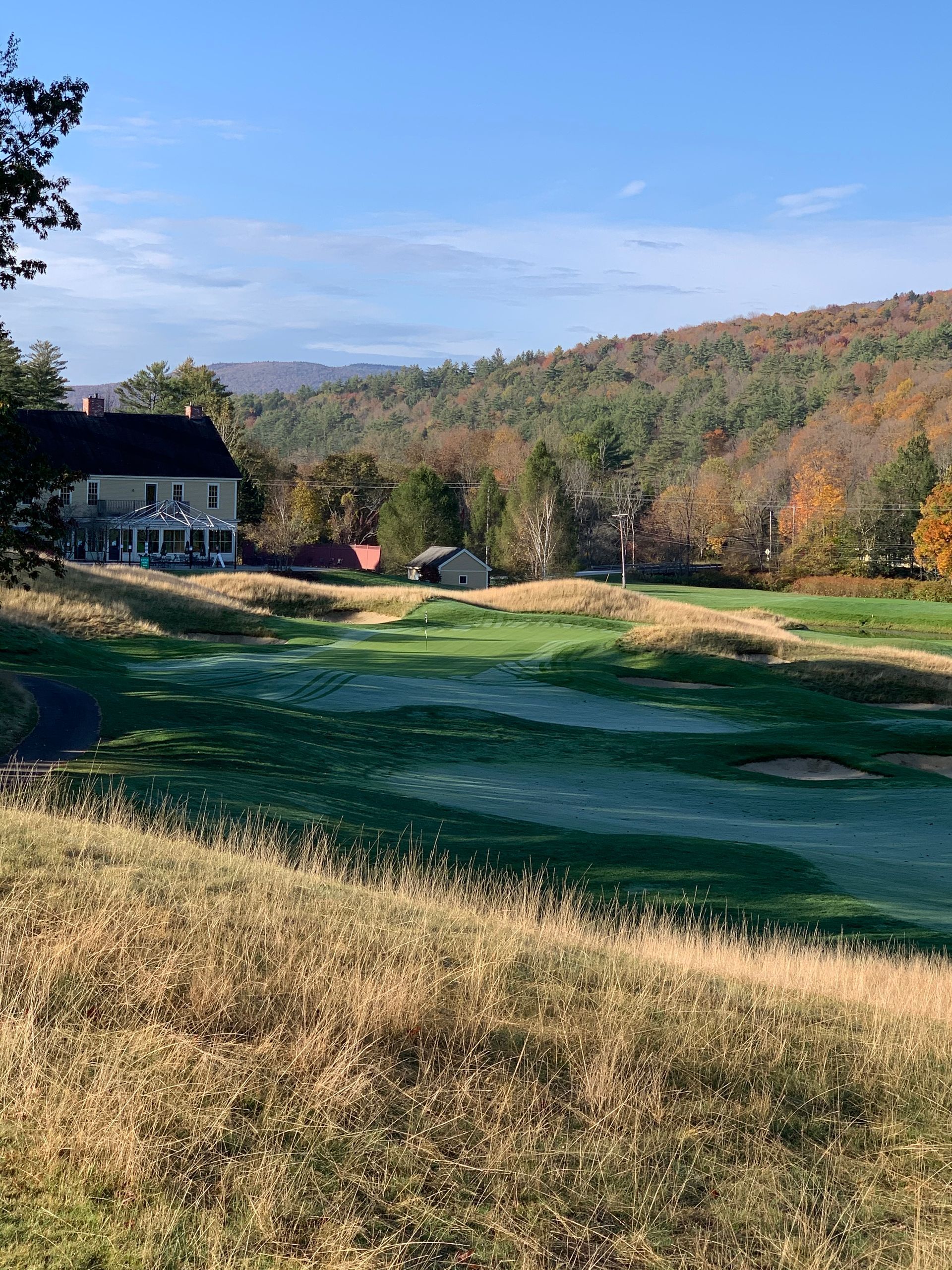 A large house is sitting on top of a hill next to a golf course.