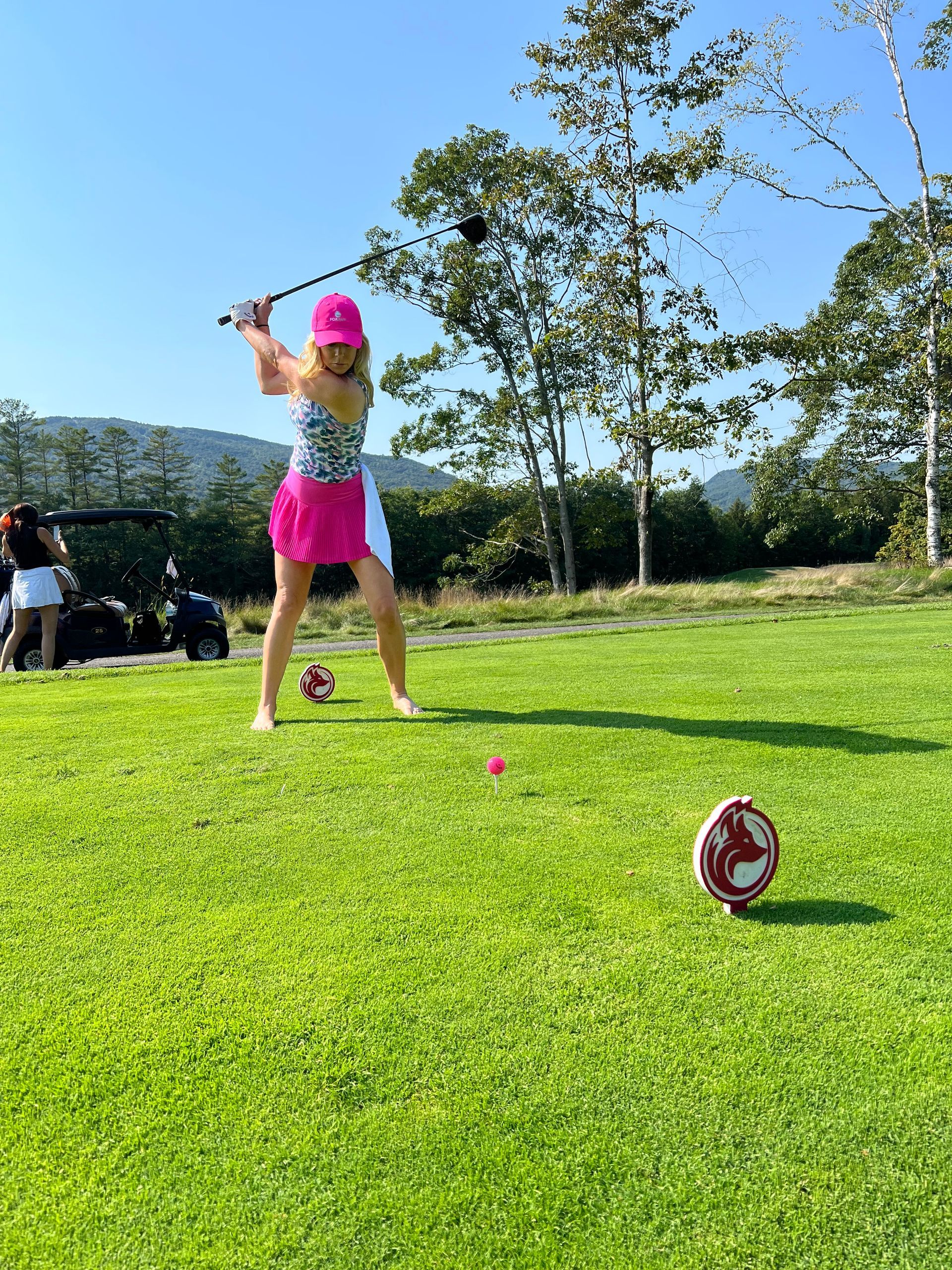 A woman is swinging a golf club on a golf course.
