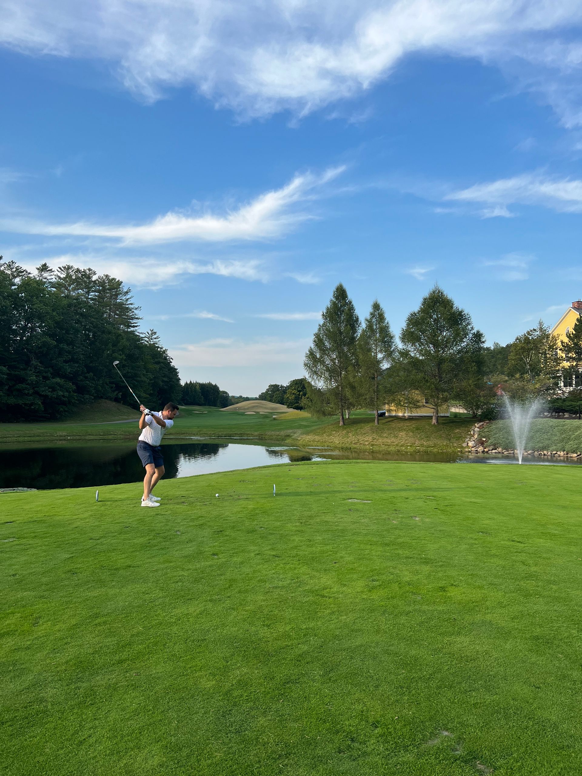 A man is swinging a golf club on a golf course.
