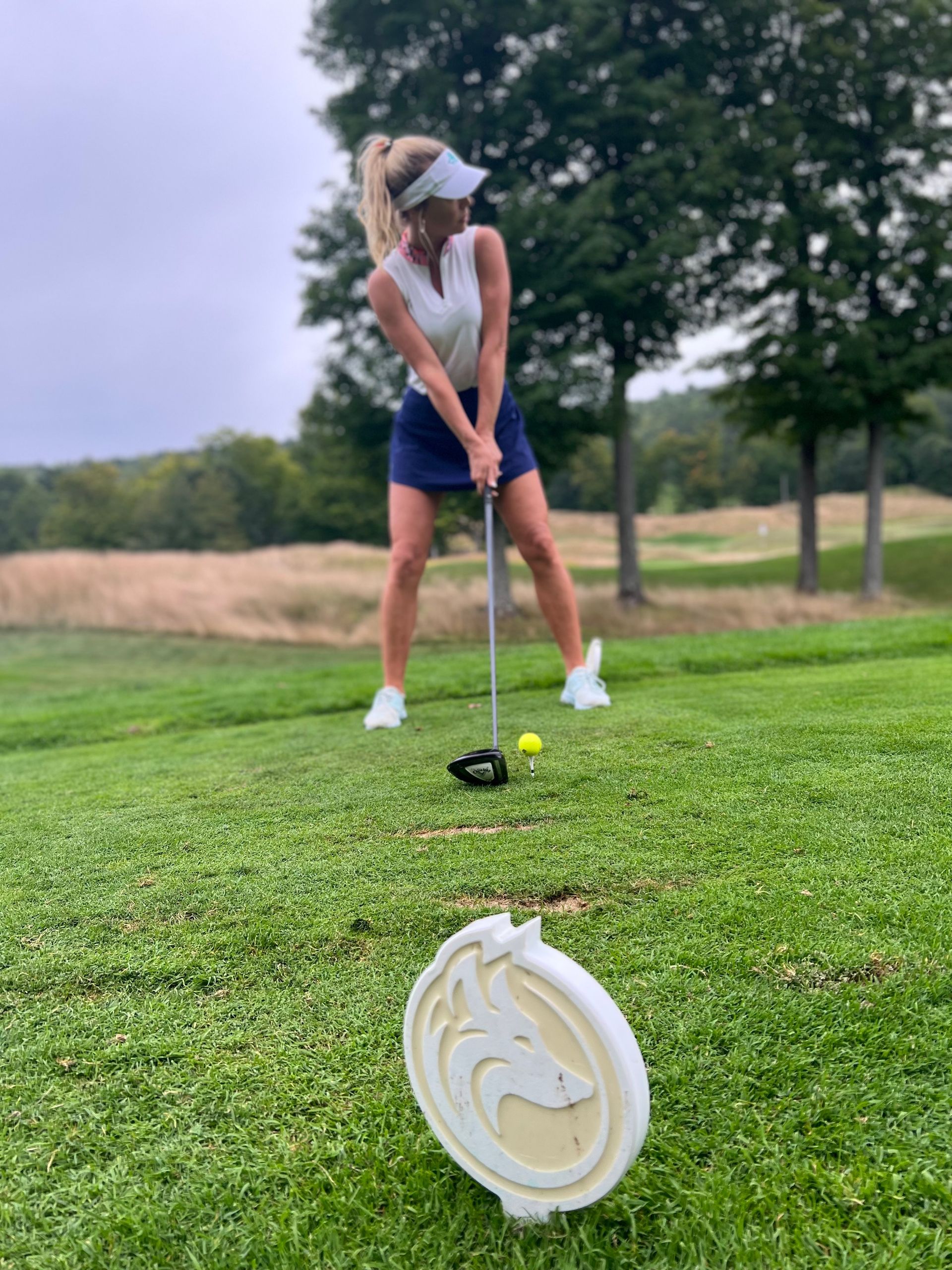A woman is swinging a golf club on a golf course.