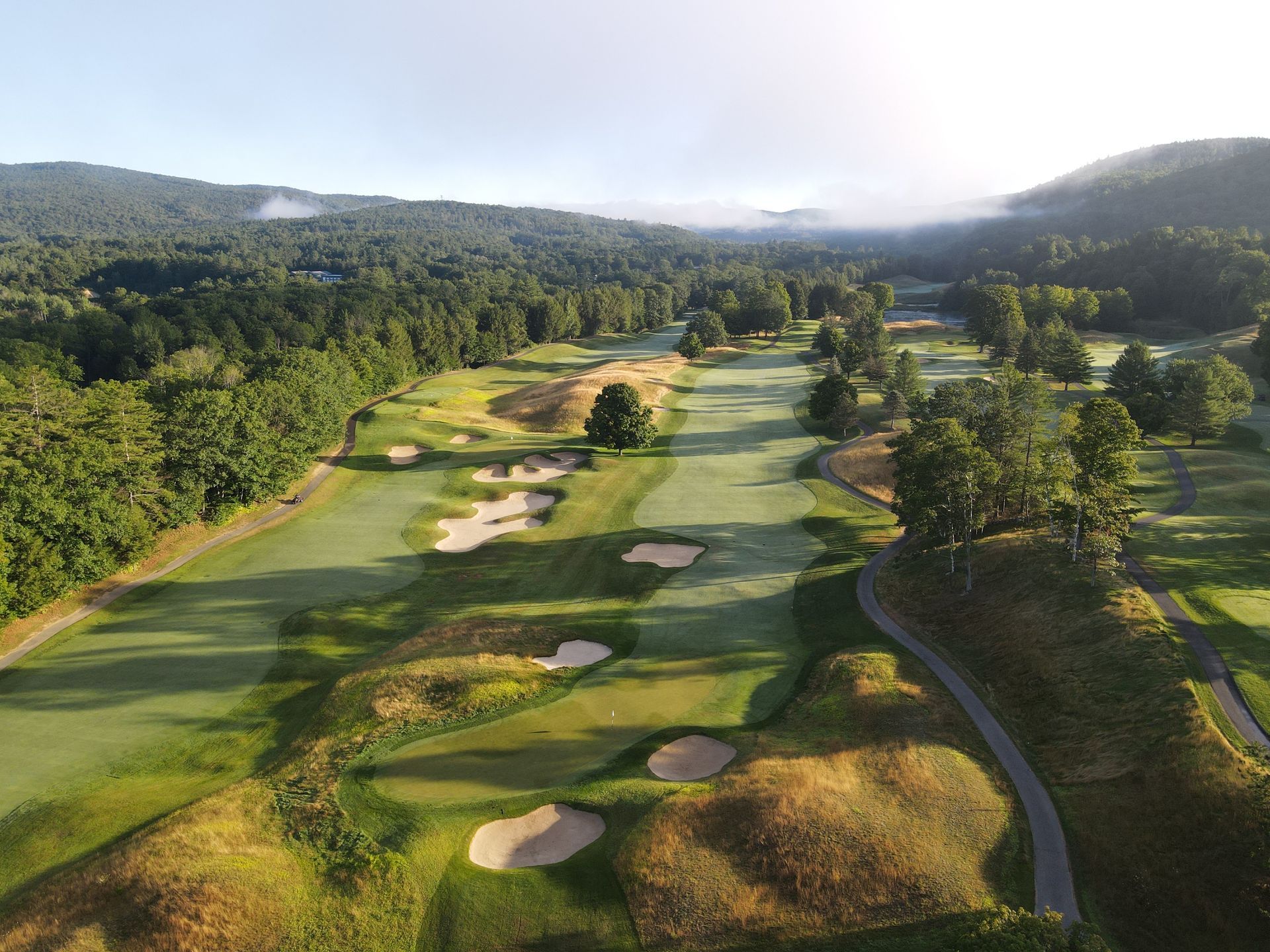 An aerial view of a golf course surrounded by trees.