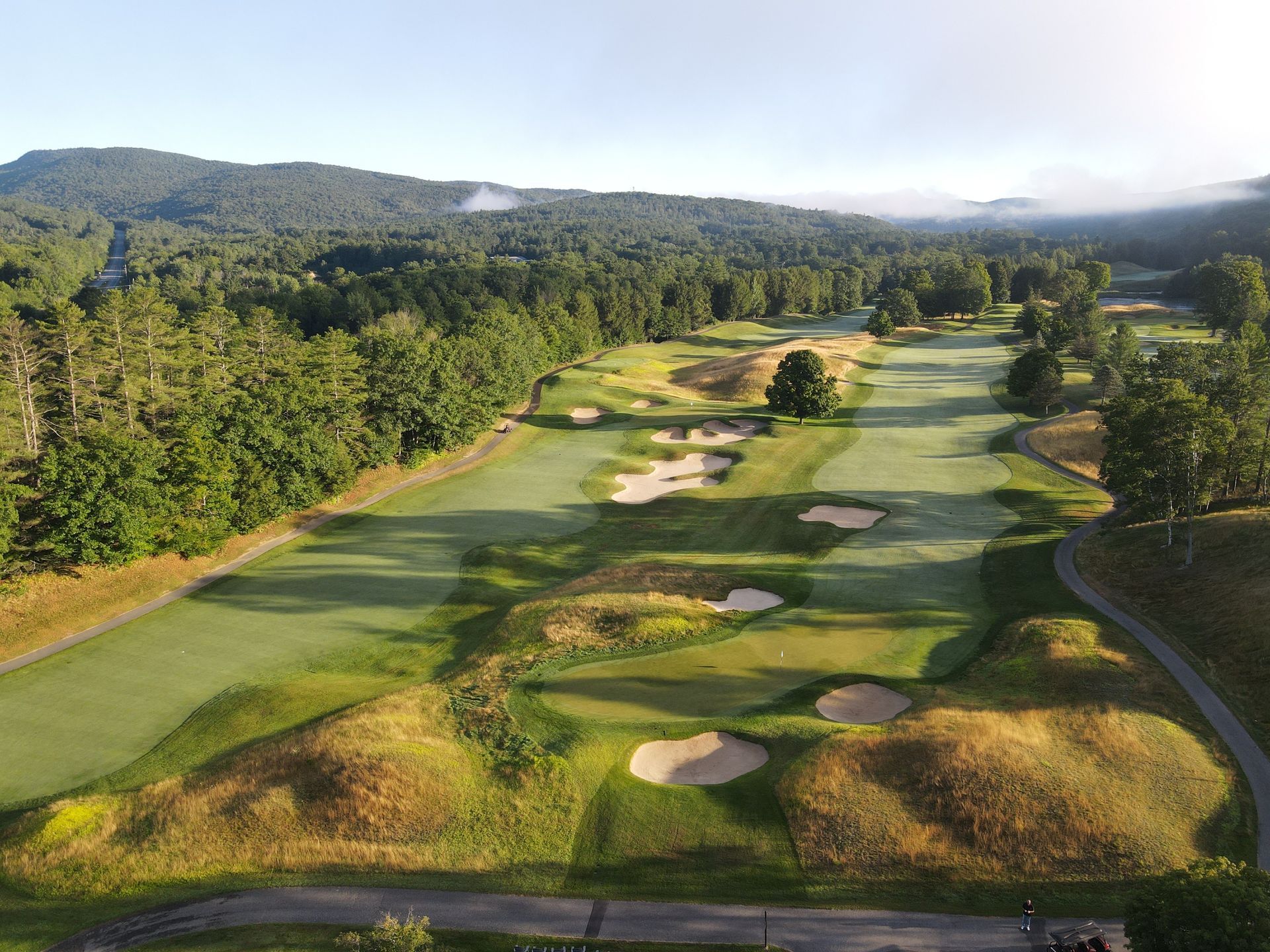 An aerial view of a golf course with mountains in the background.