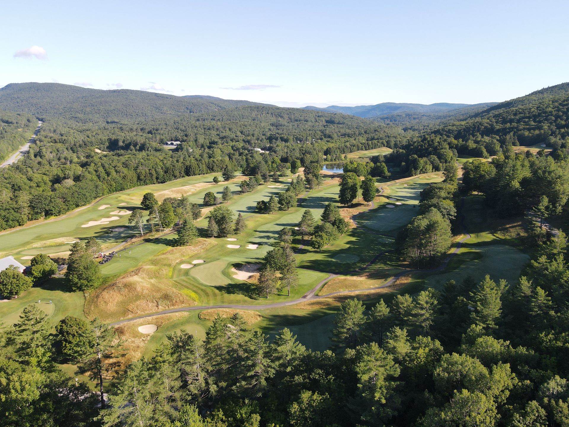 An aerial view of a golf course surrounded by trees and mountains.