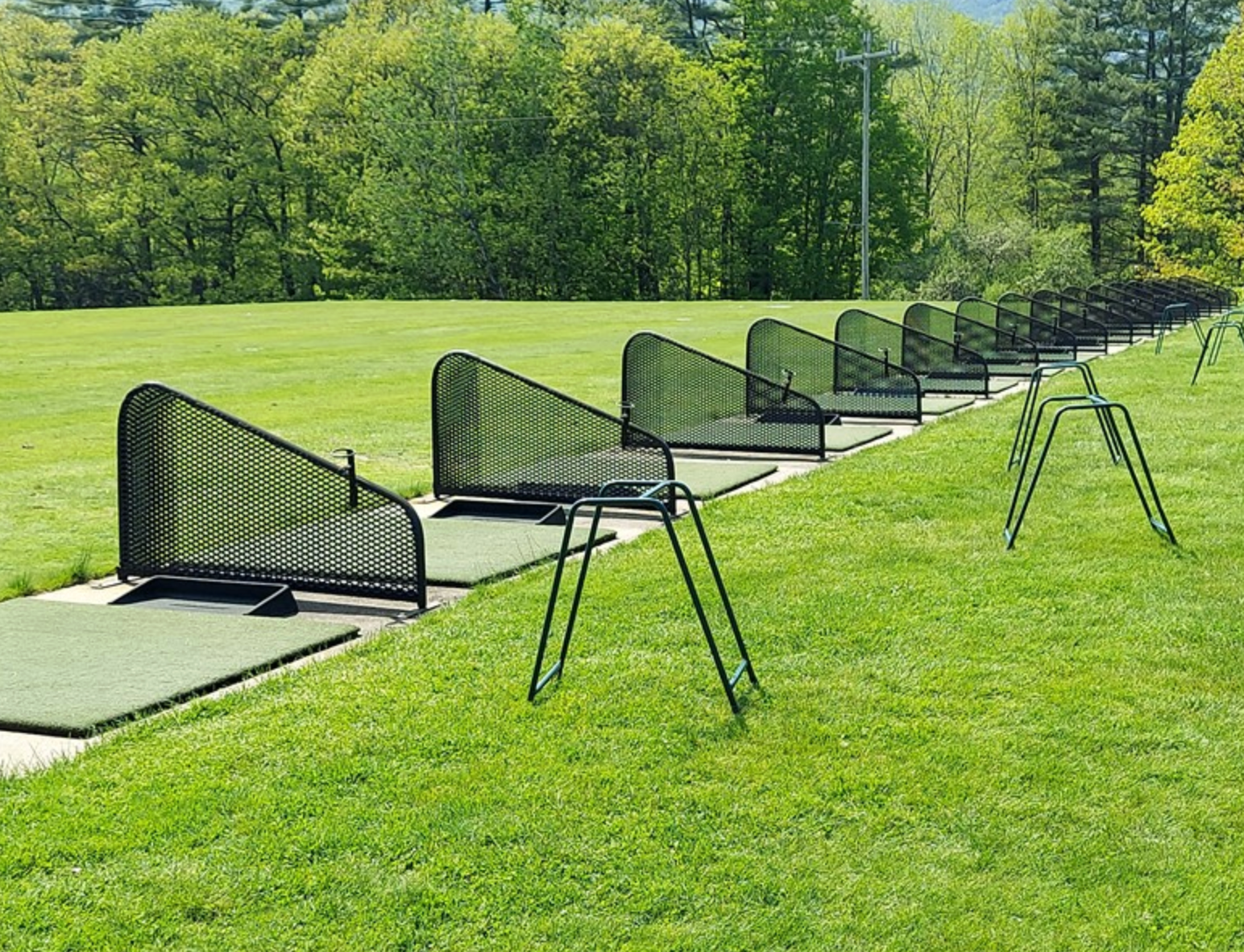 A row of metal fences sitting on top of a lush green field.