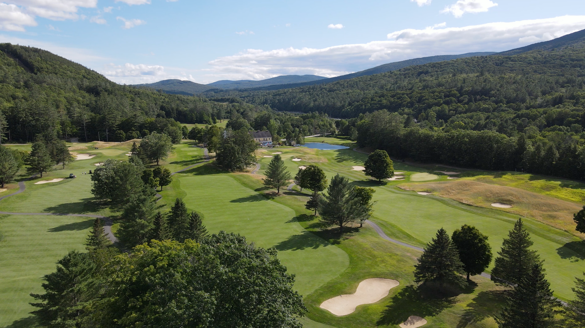 An aerial view of a golf course surrounded by trees and mountains.