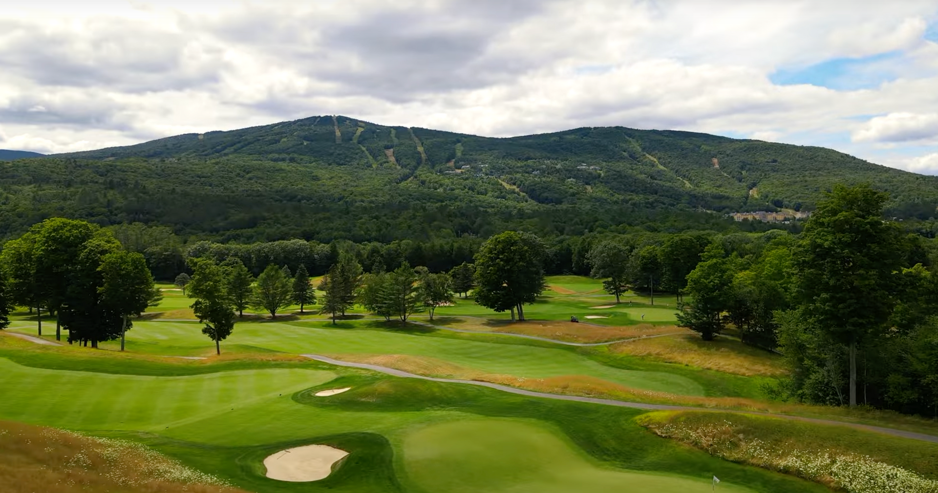 An aerial view of a golf course with mountains in the background.