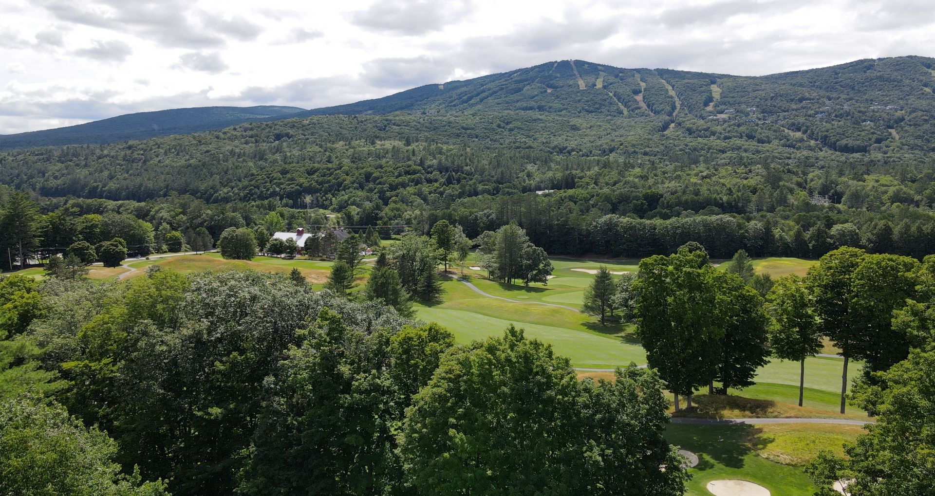 An aerial view of a golf course surrounded by trees and mountains.