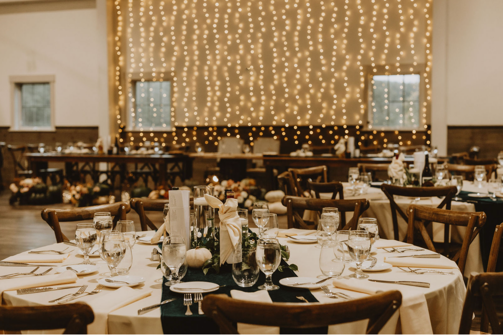 A large room with tables and chairs set up for a wedding reception.