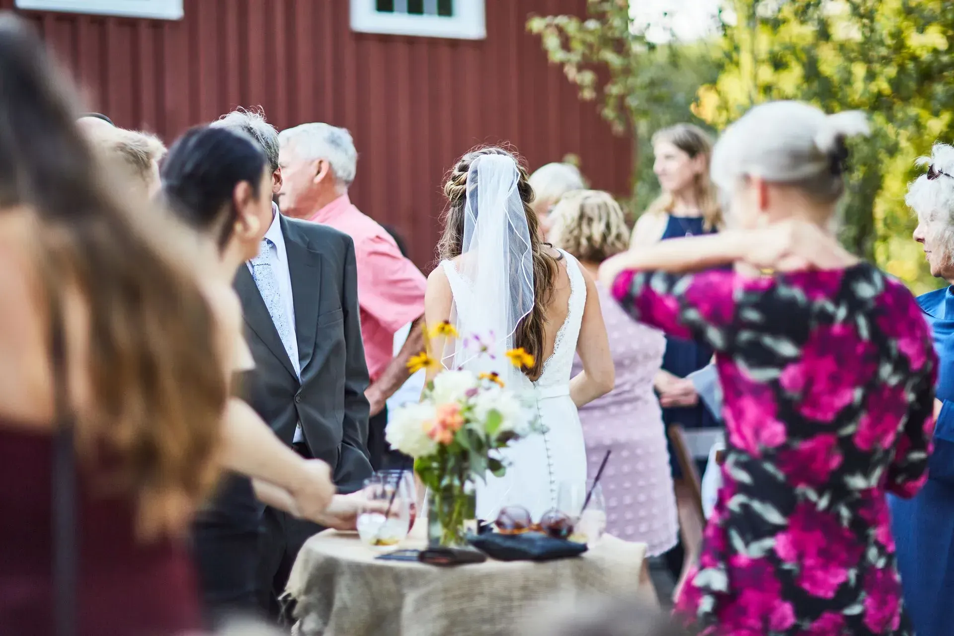 A bride and groom are standing in a crowd of people at a wedding reception.