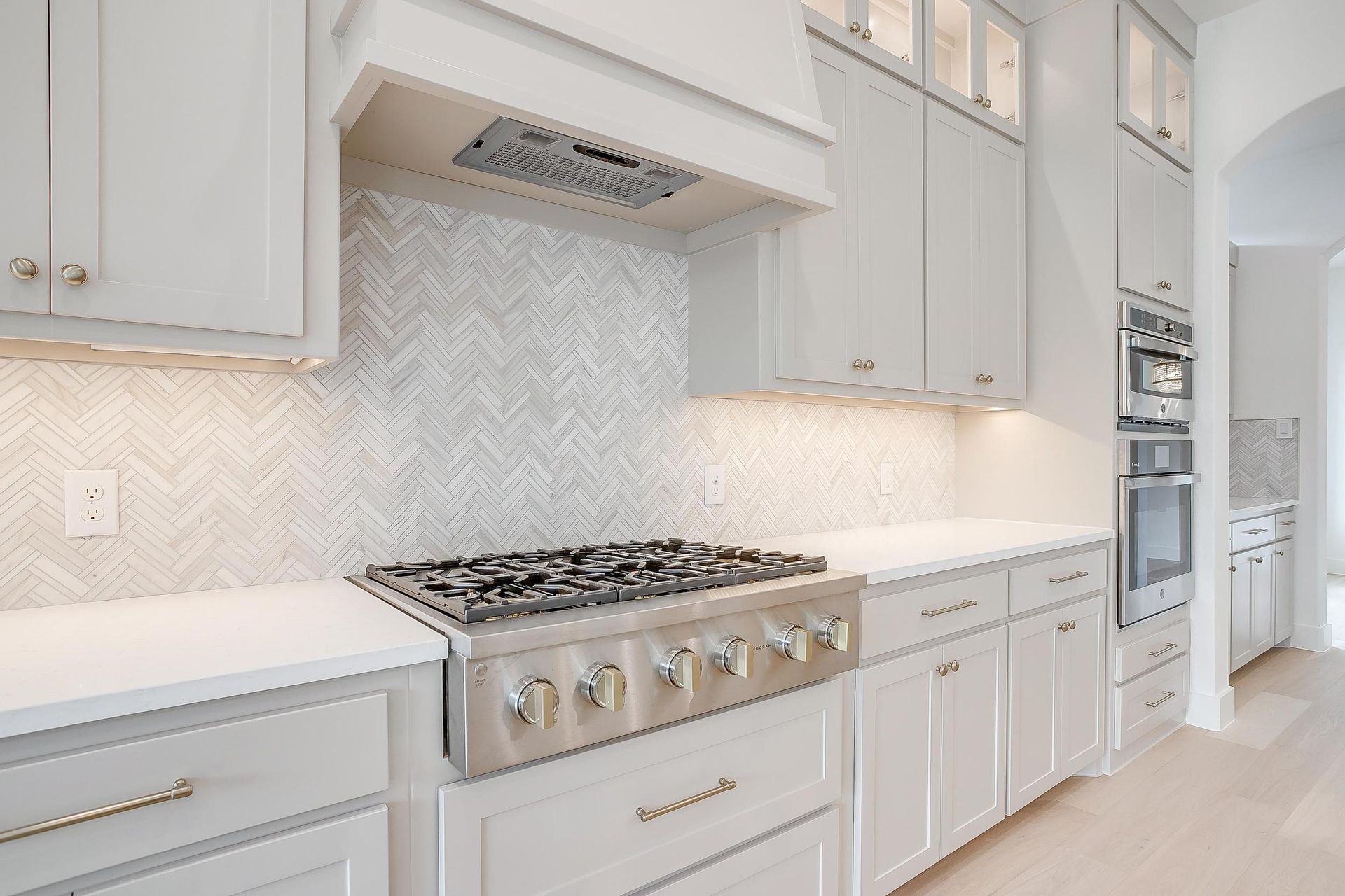 A kitchen with white cabinets and a stove top oven.