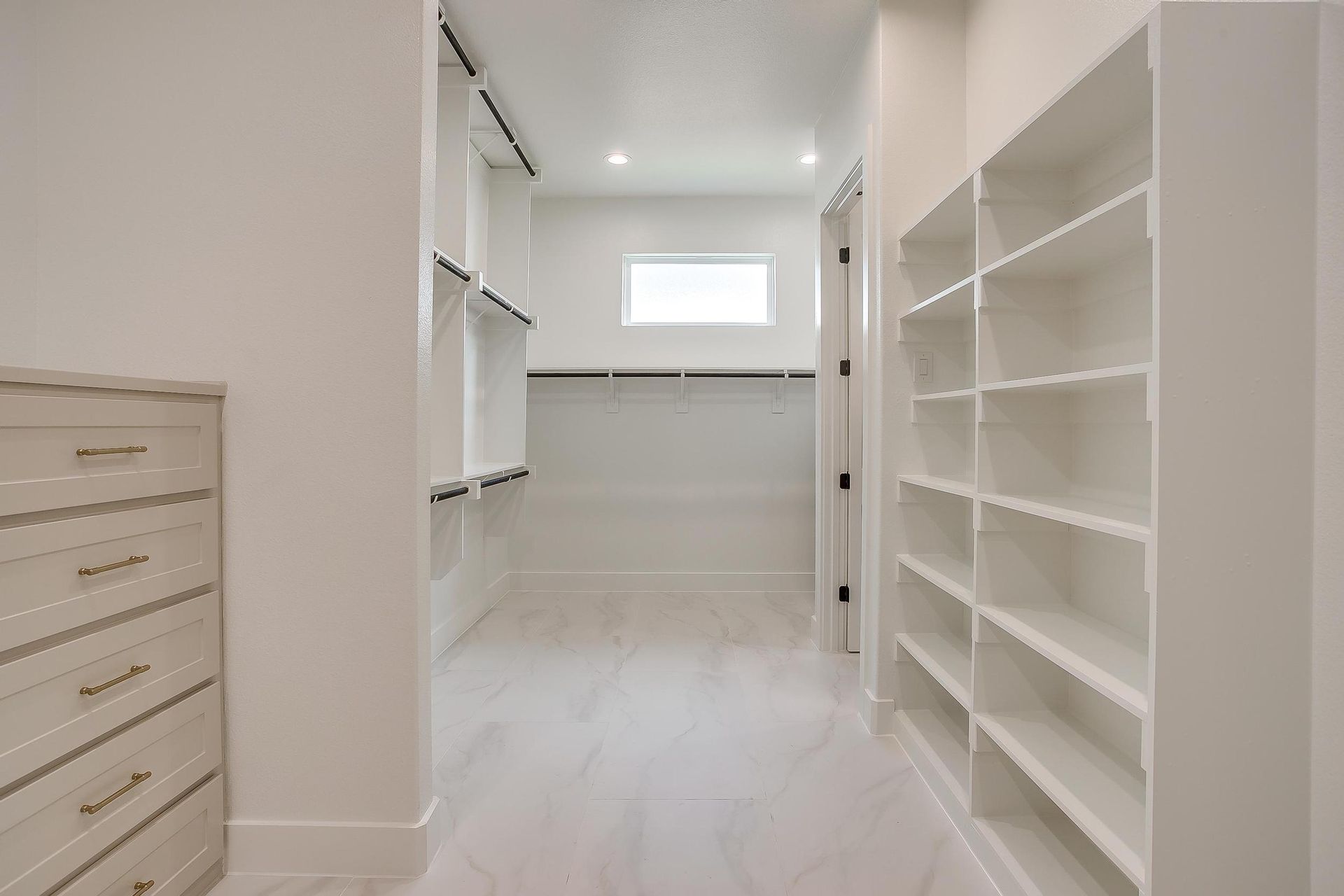 A walk in closet with lots of shelves and a window.