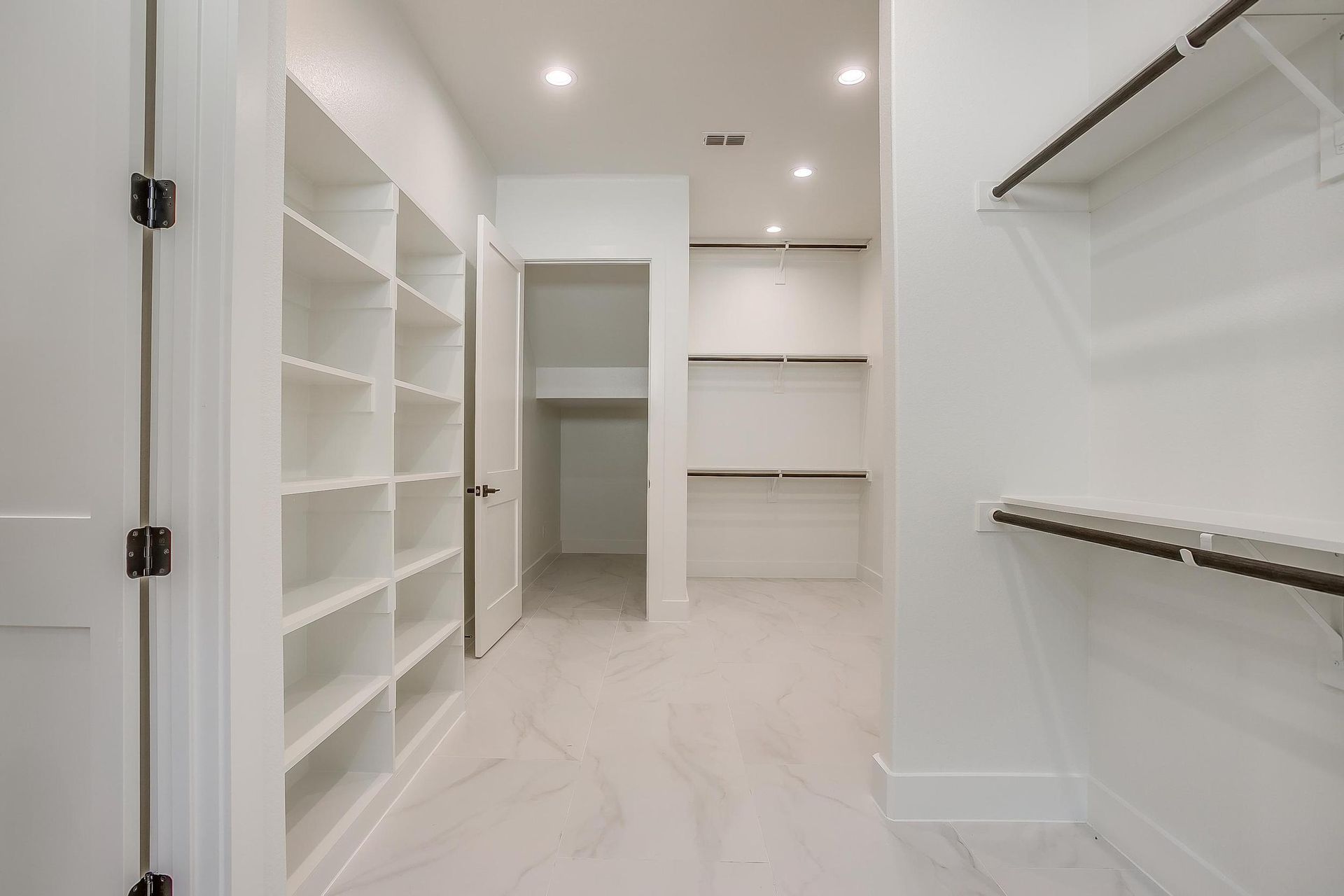 A walk in closet with lots of shelves and a door.