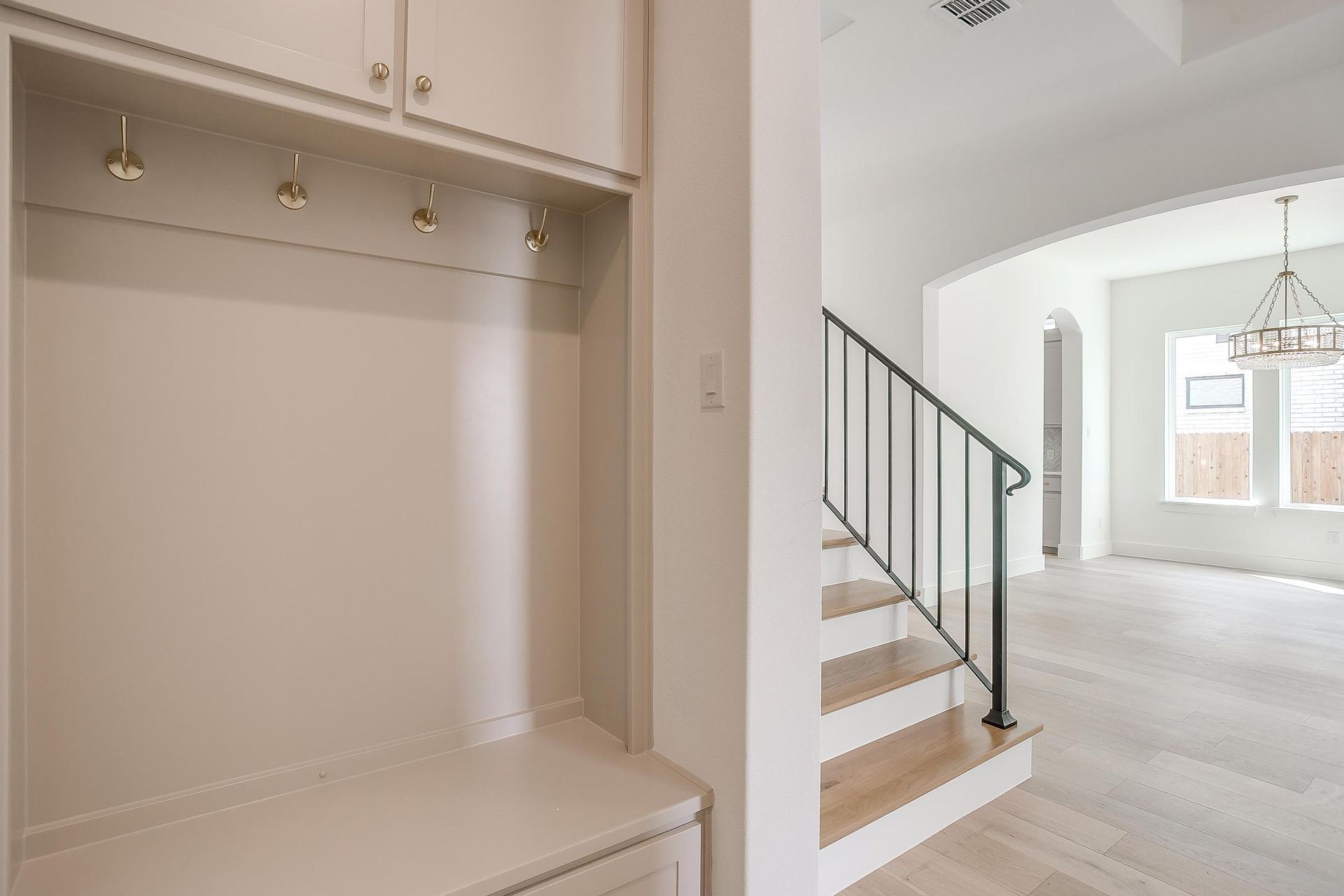 A hallway with a bench and stairs in a house.