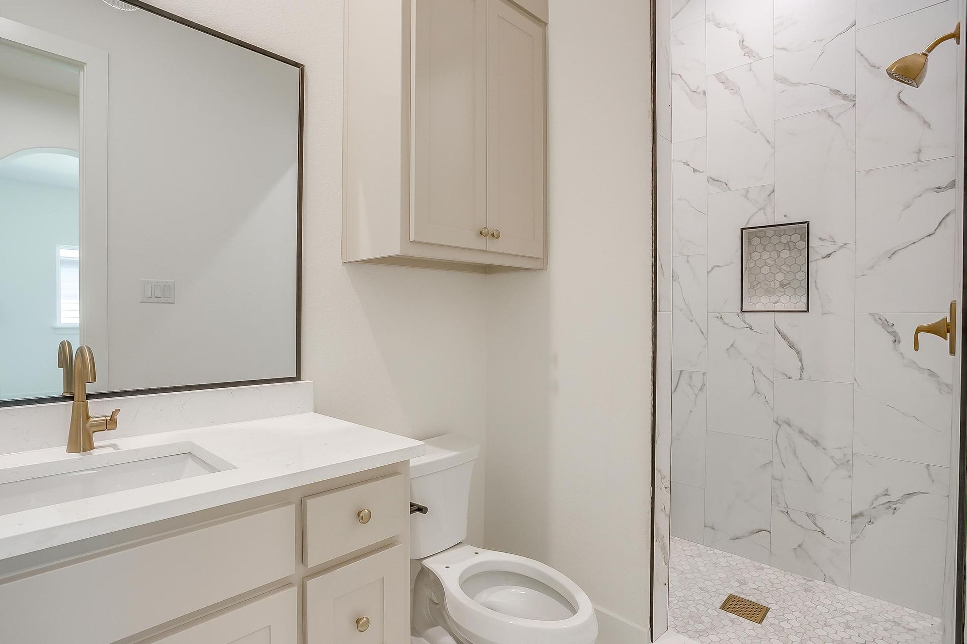 A bathroom with a toilet , sink , mirror and walk in shower.
