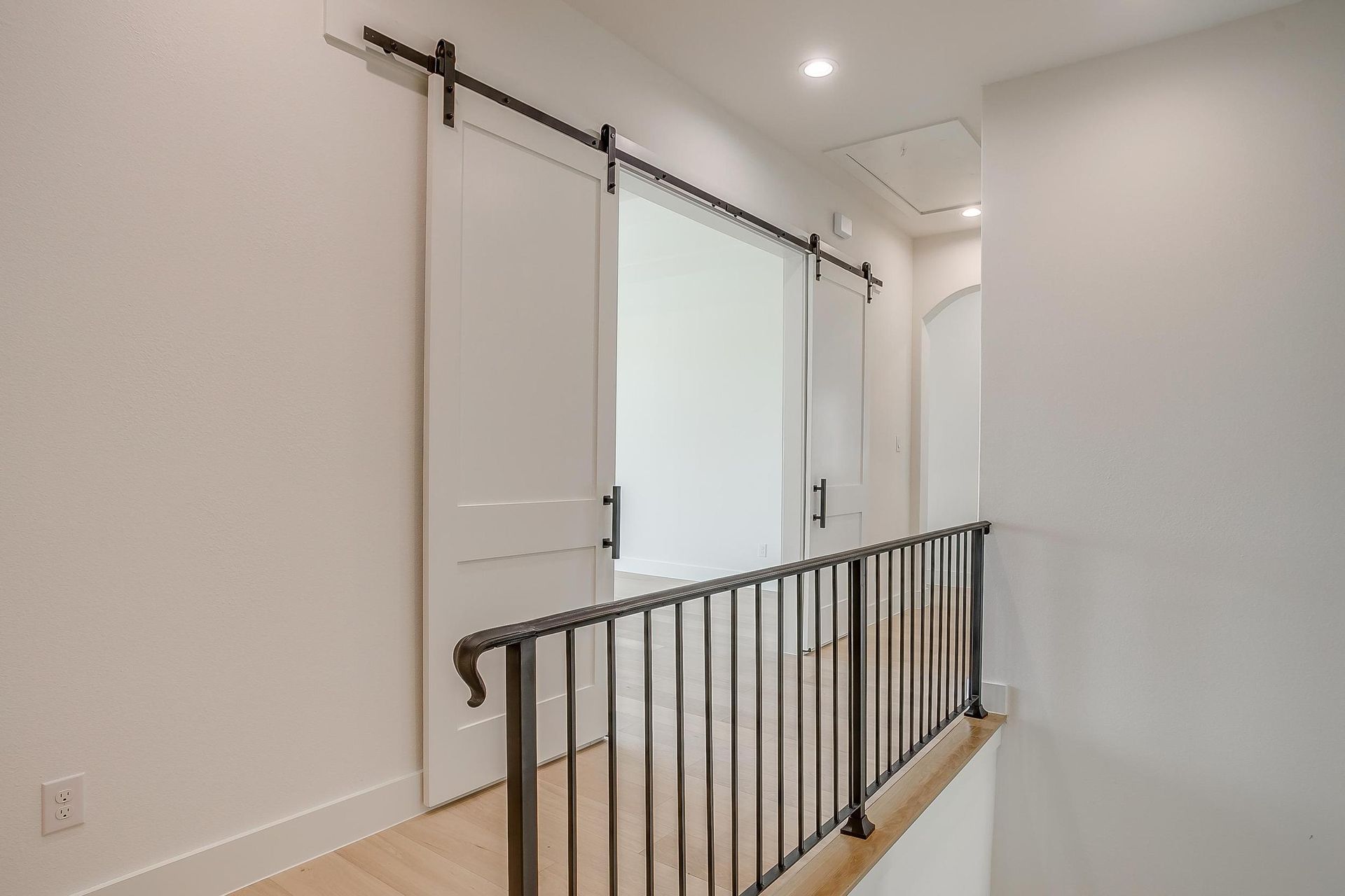 A hallway with sliding barn doors and a railing.