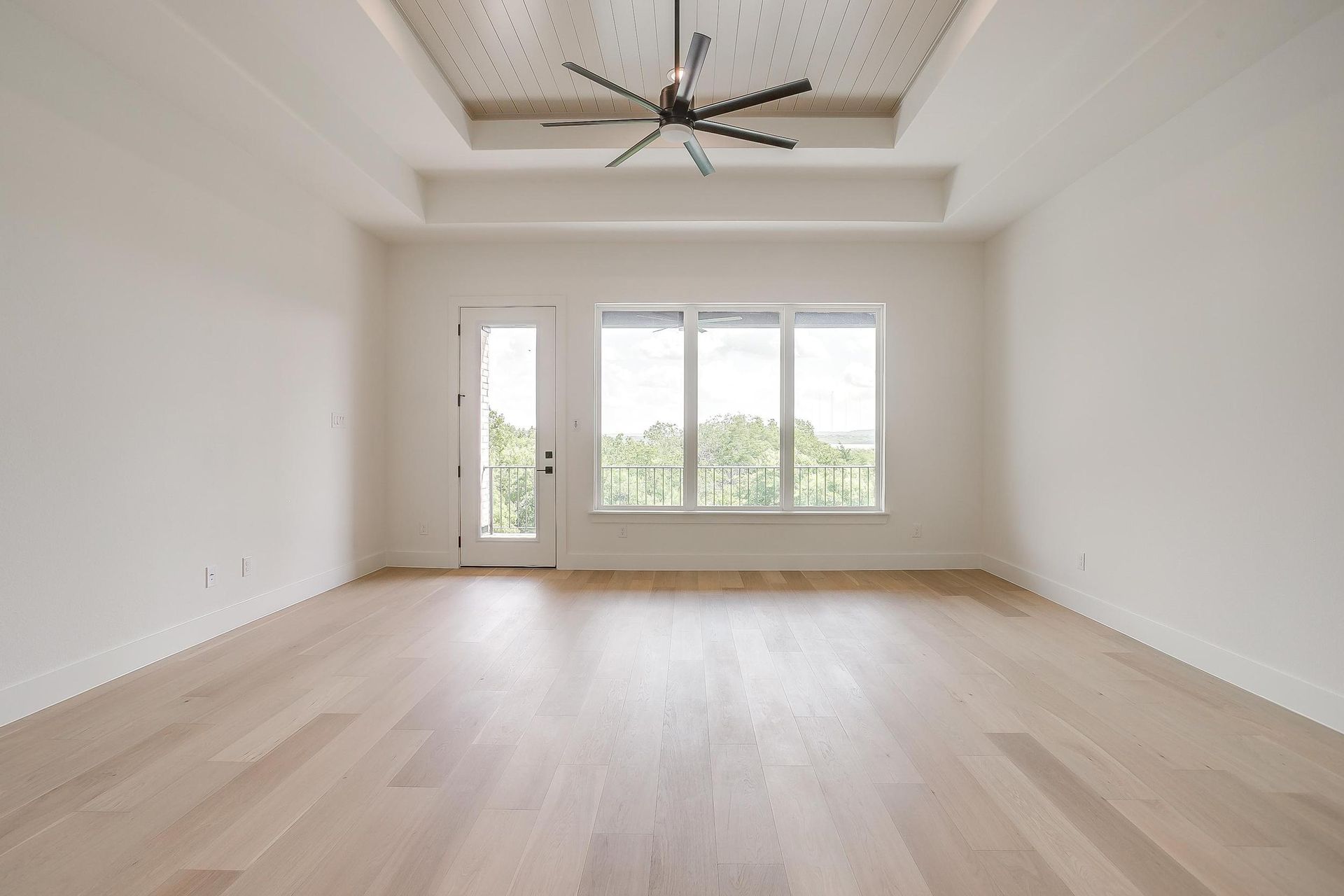 An empty living room with hardwood floors and a ceiling fan.
