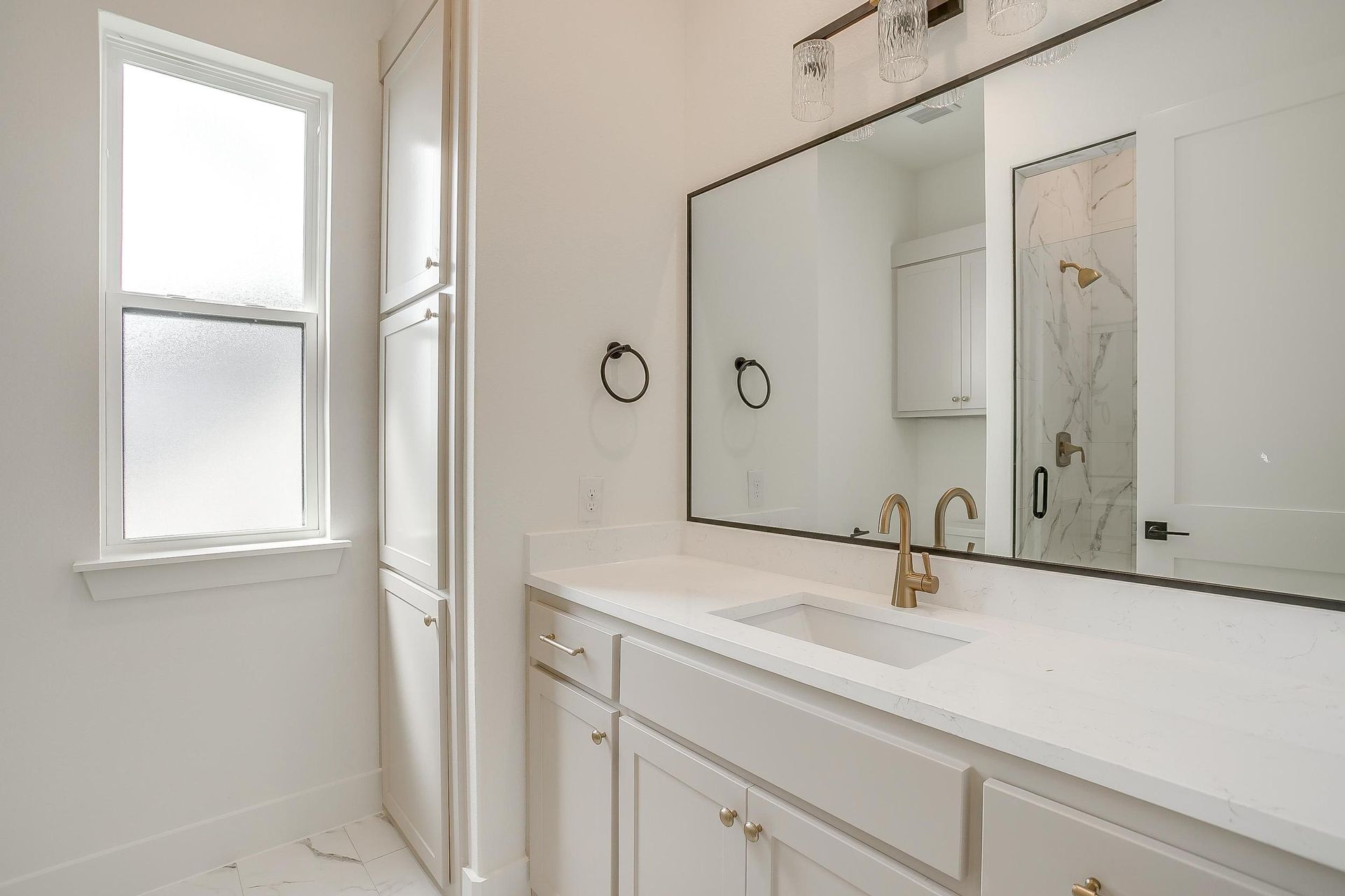 A bathroom with a sink , mirror and window.