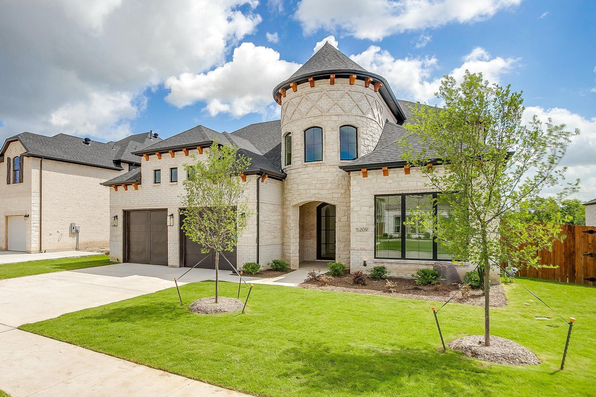 A large house with a tower on top of it is sitting on top of a lush green lawn.