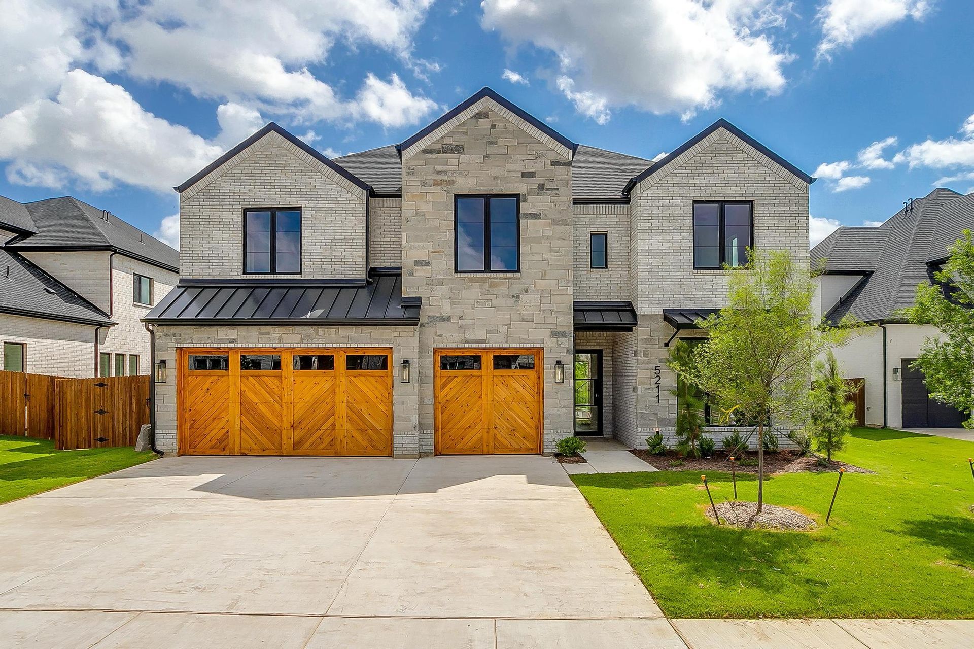 A large brick house with three wooden garage doors.